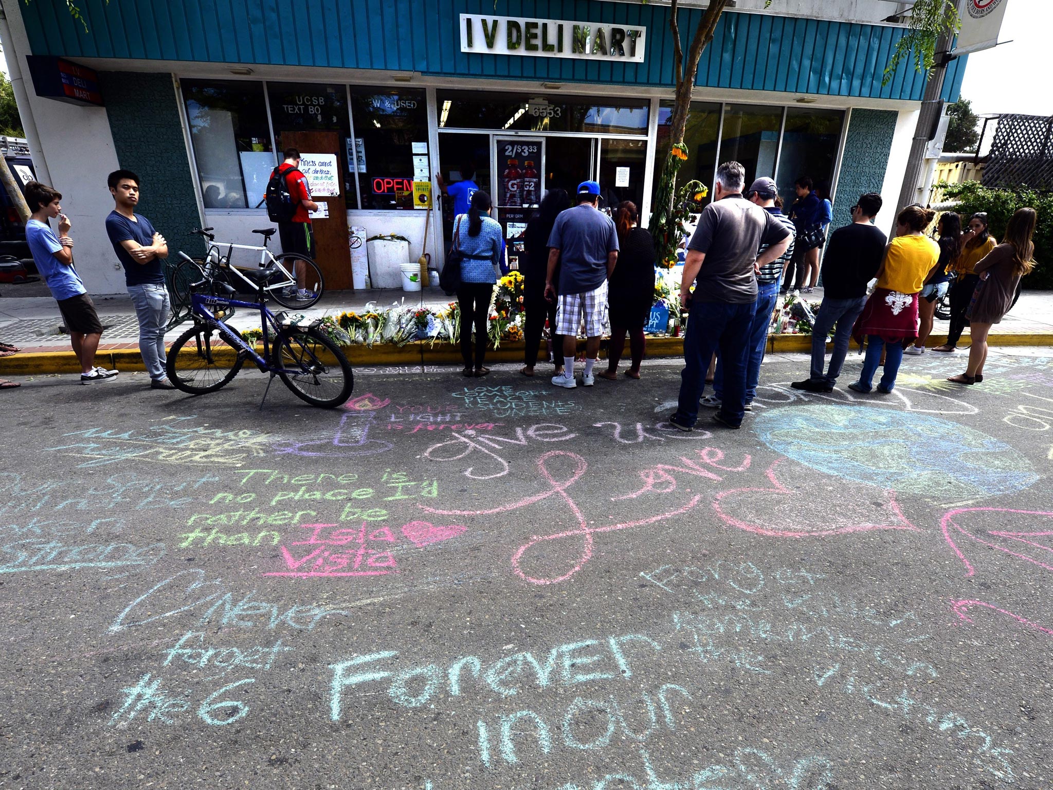 'Forever in Our Hearts' and other messages are written in chalk in front of the Isla Vista Deli Mart