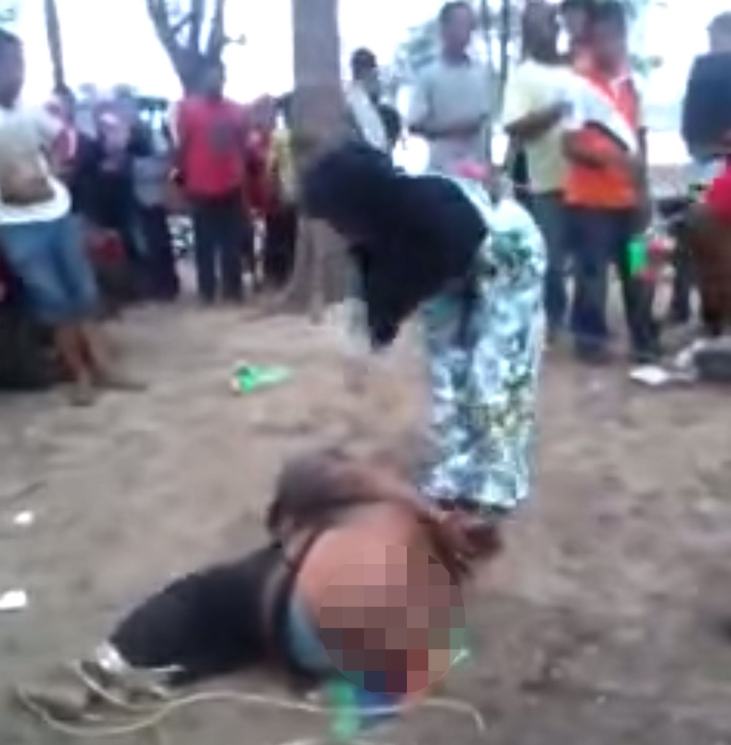 The video shows a man with his hands and feet bound being hit repeatedly by a woman with a stick