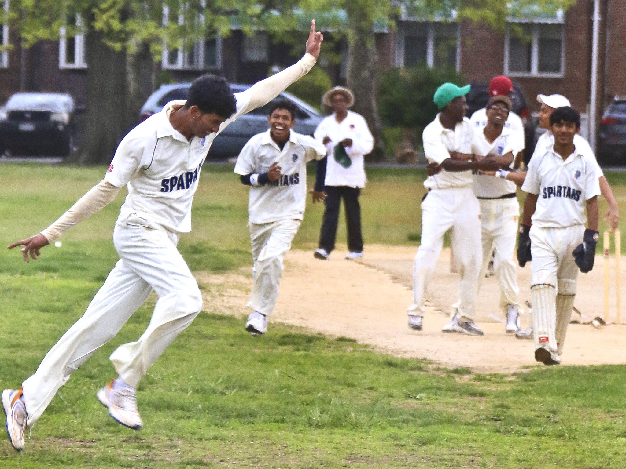 John Adams High School's Derick Narine celebrates after bowling out a Midwood High School batsman, during a Public School Athletic League cricket match in Brooklyn, New York