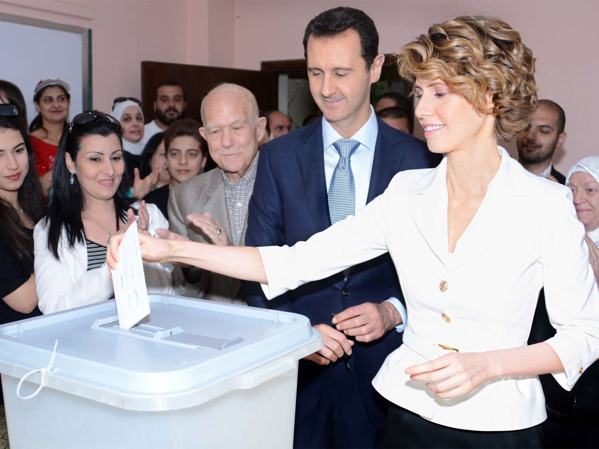 The Syrian President Bashar al-Assad watches his wife Asma cast her vote at a polling station in Damascus (Getty)