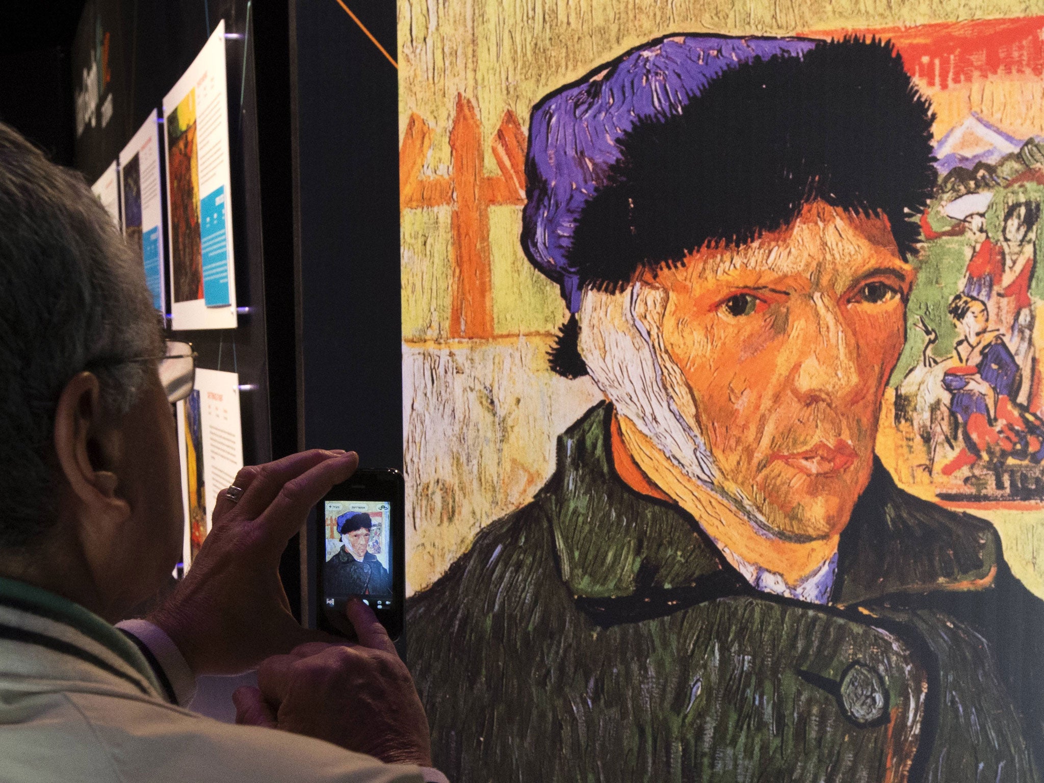 A visitor takes pictures of a self-portrait by Dutch painter van Gogh, showing his bandaged head where his ear used to be, at an exhibition in Tel Aviv, Israel.