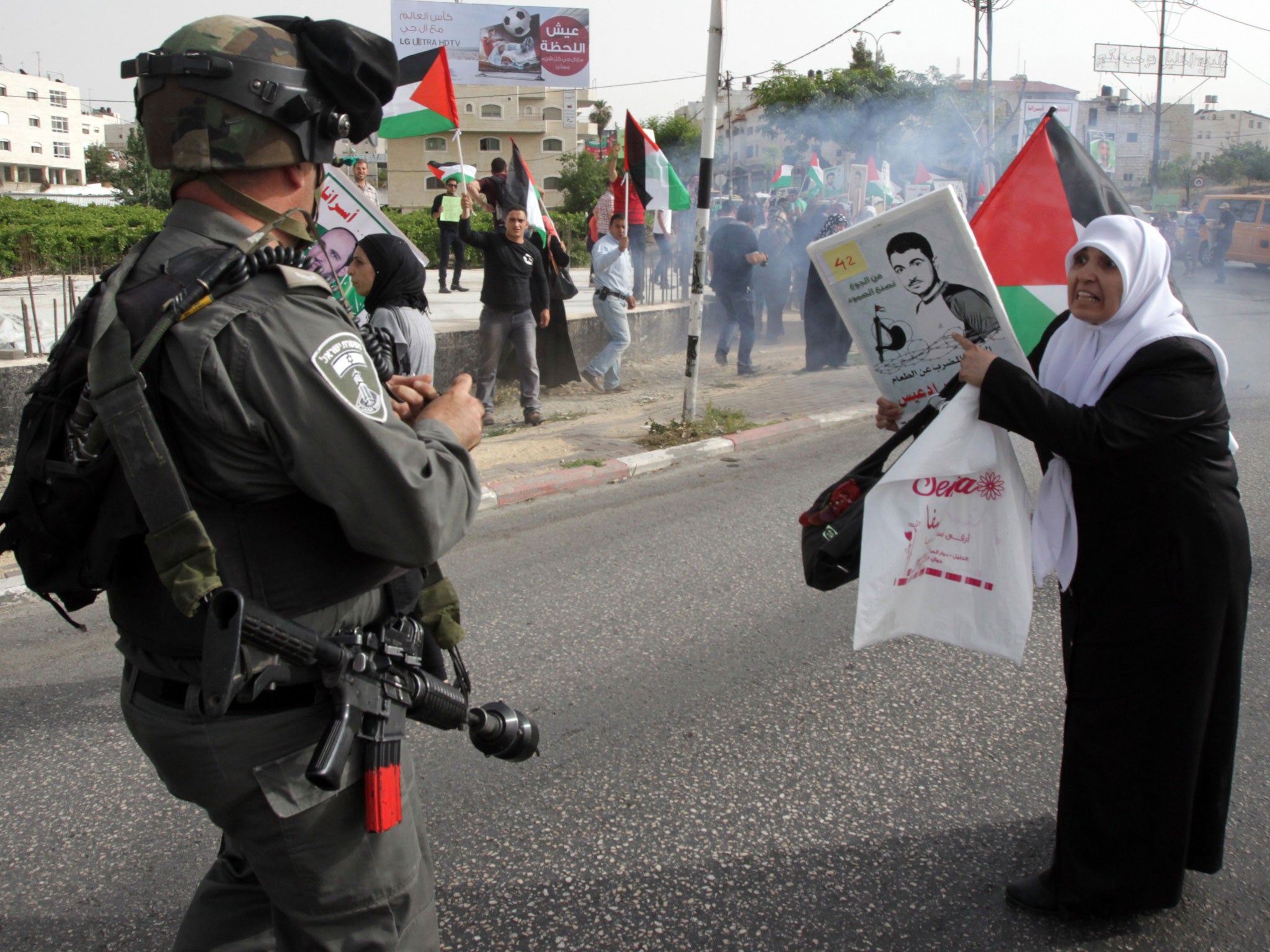 A Palestinian woman points at a portrait of a loved one detained in an Israeli jail, in front of a member of the Israeli security forces during a demonstration in the West Bank city of Hebron against the Israeli occupation and in support of Palestinians b