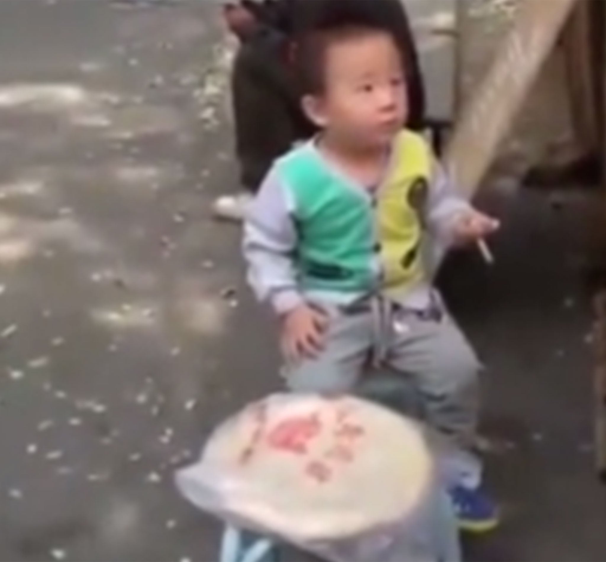 Onlookers do nothing to intervene as the child holds a cigarette