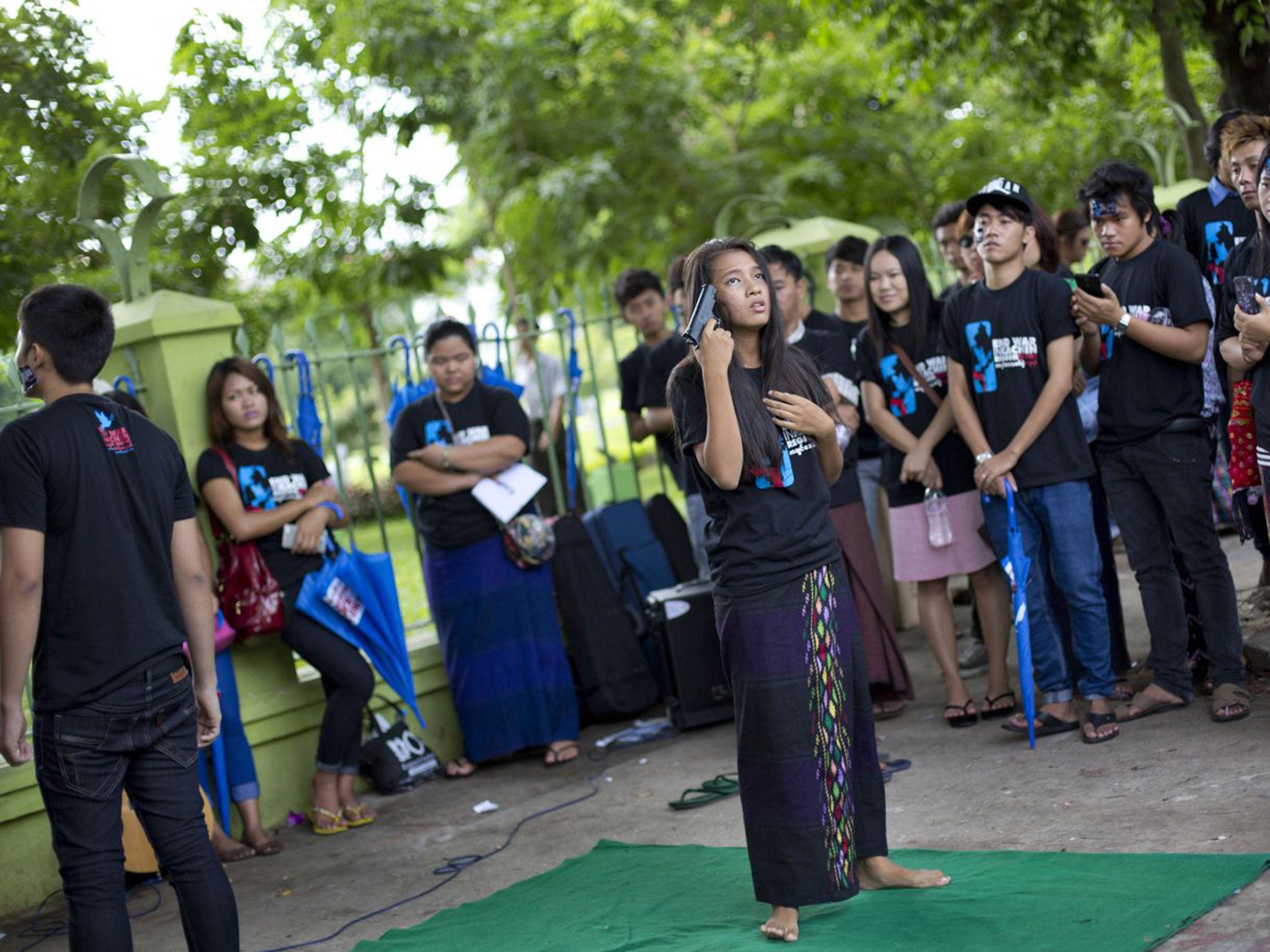 A young Kachin activist in Myanmar performs a piece of street theatre depicting a victim of war rape attempting to commit suicide