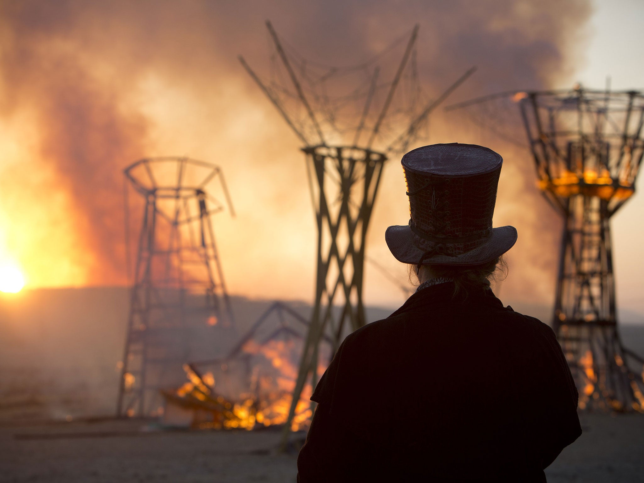 A man looks at a wooden sculpture that was set on fire during Israel's first Midburn Festival, modeled after the popular Burning Man Festival held annually in Nevada's Black Rock Desert, near the Israeli kibbutz of Sde Boker