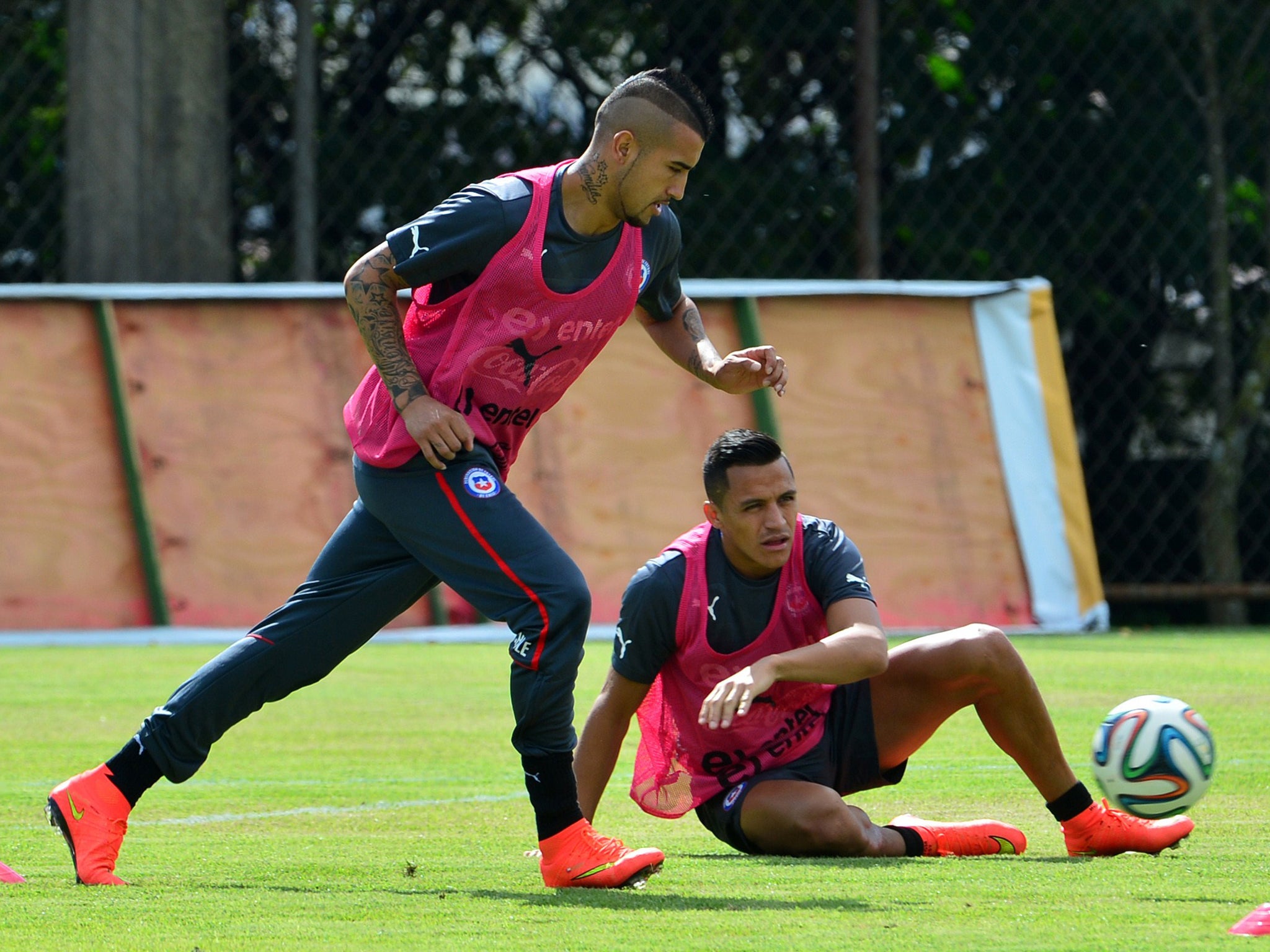 Chile's national football team midfielder Arturo Vidal (L) controls the ball as his teammate forward Alexis Sanchez (R) watches on during a training session