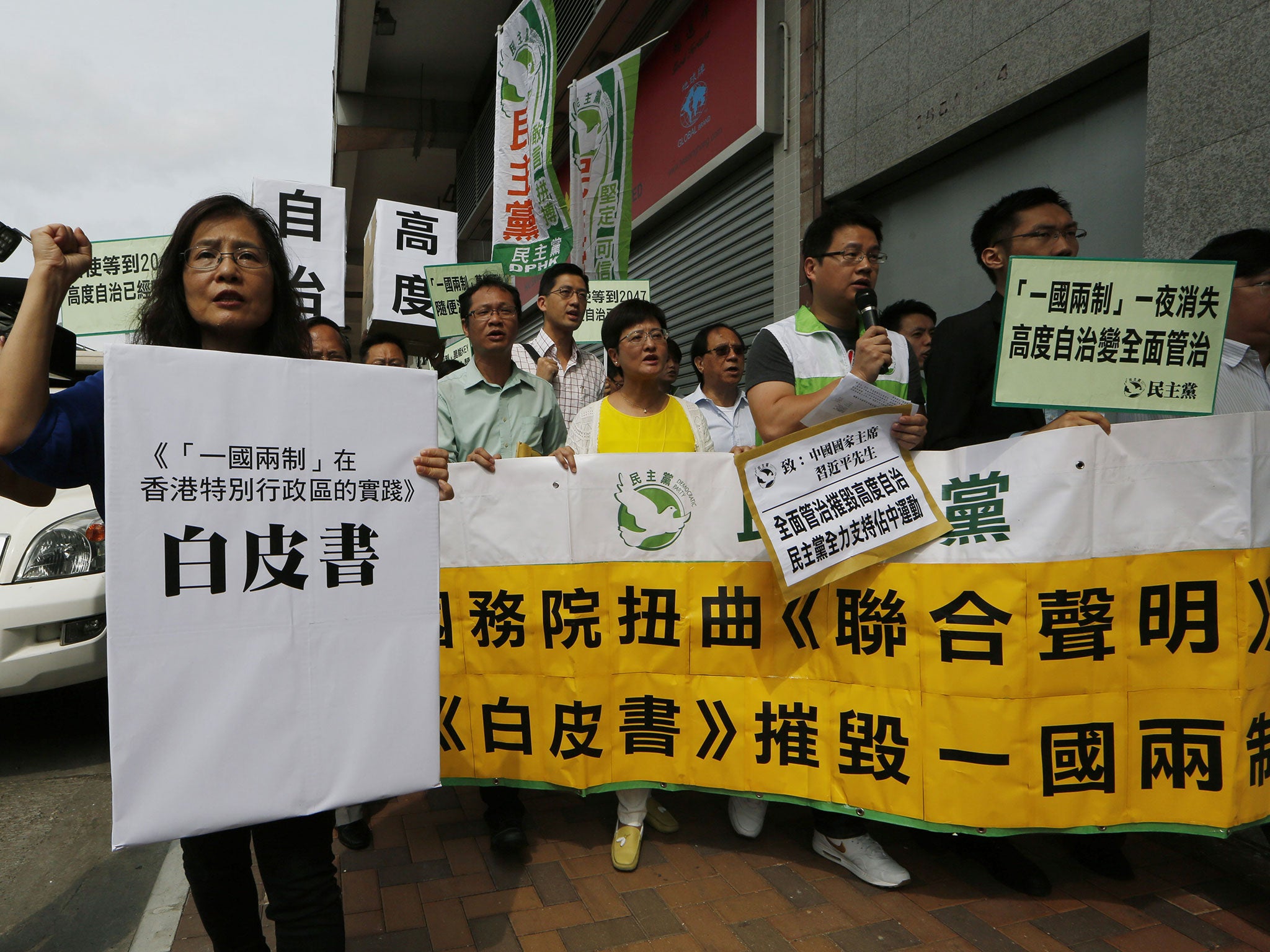 Protesters hold banners and the mock "white paper" released by Beijing State Council on Tuesday saying it holds ultimate control over the former British colony, near the Chinese liaison office in Hong Kong