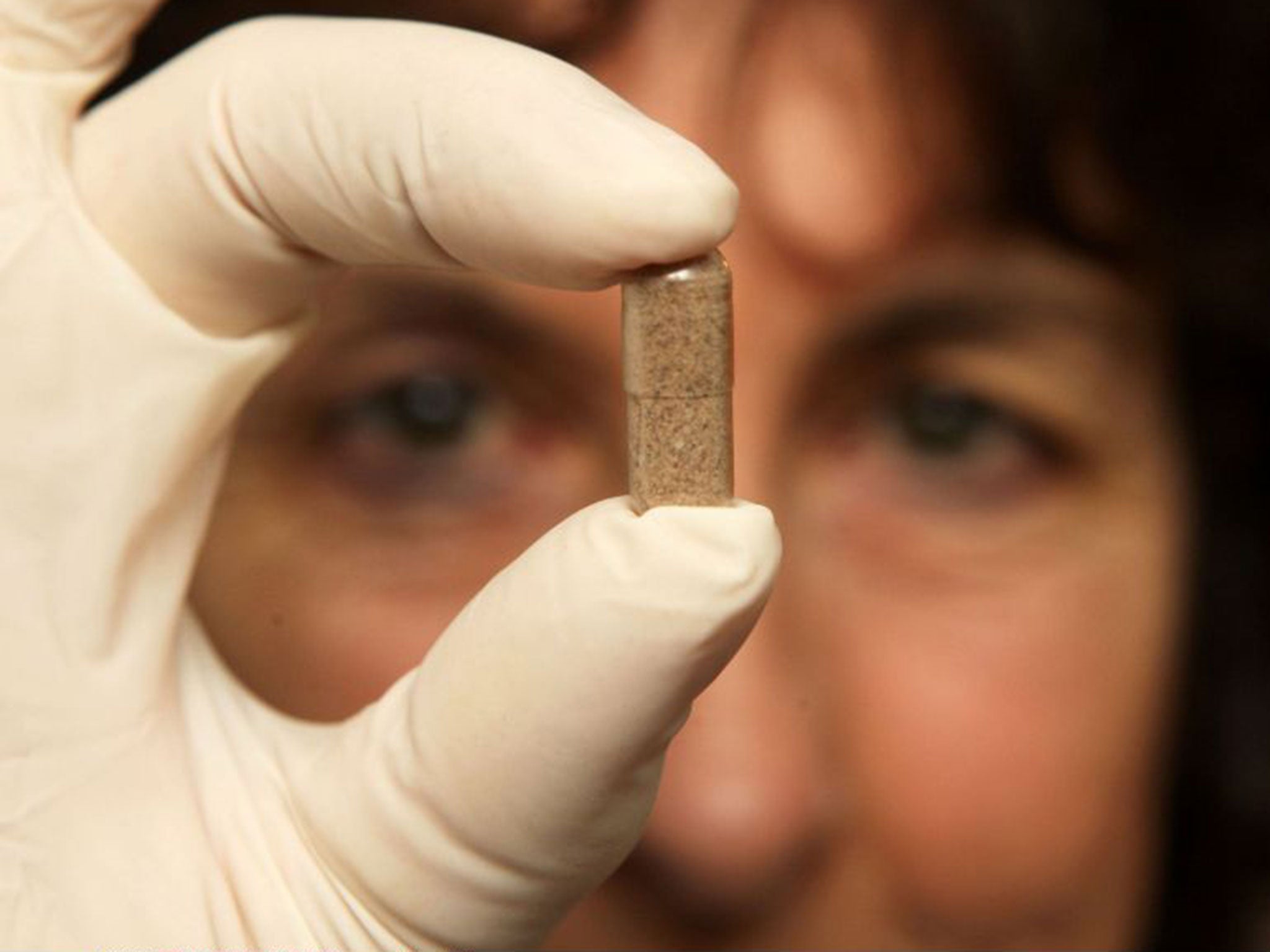 A woman holds up a dried-placenta capsule. The product was last year caught up in new GM food rules