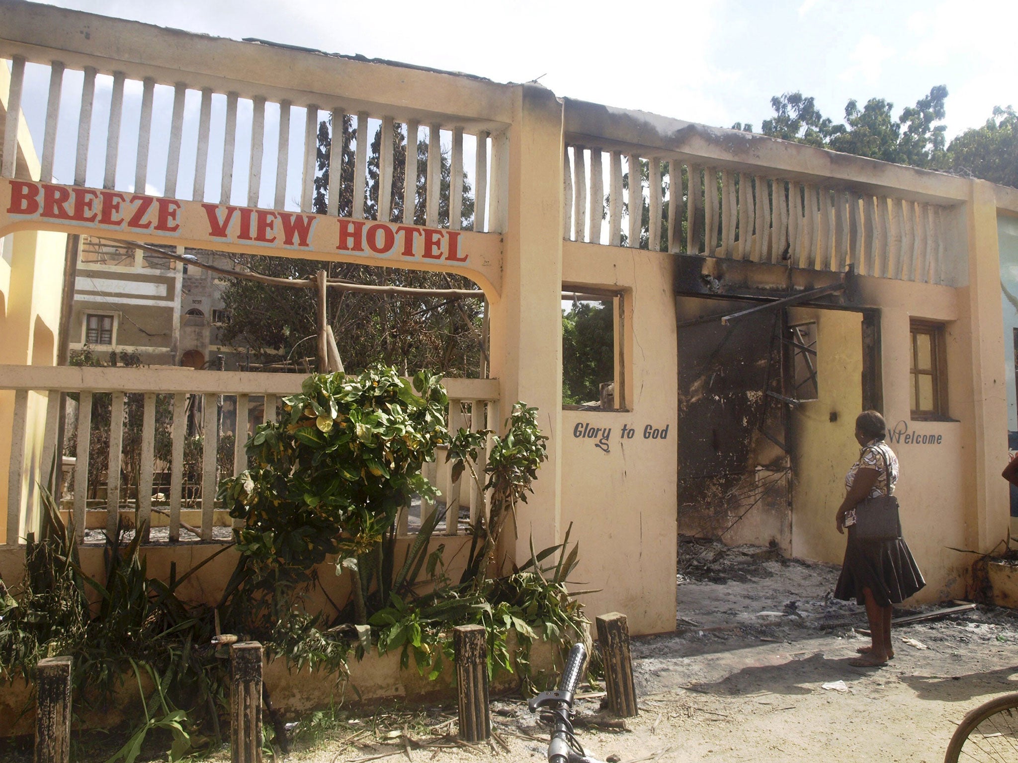 A woman observes the remains of the Breeze View Hotel, where residents watching World Cup soccer tournament, were attacked and killed by militants, in the town of Mpeketoni, about 100 kilometers (60 miles) from the Somali border on the coast of Kenya