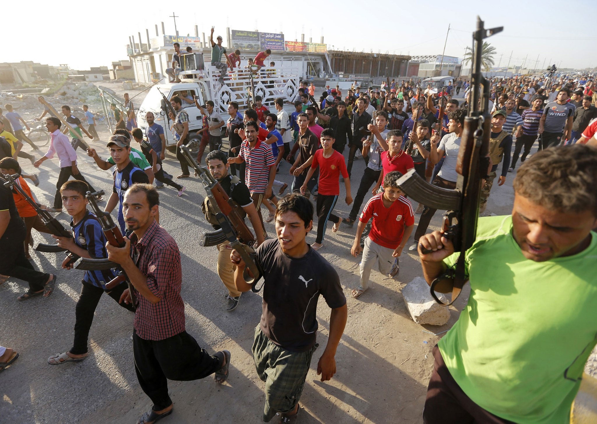 Volunteers for the Iraqi Army carry weapons during a parade in the streets in Al-Fdhiliya district, eastern Baghdad June 15, 2014