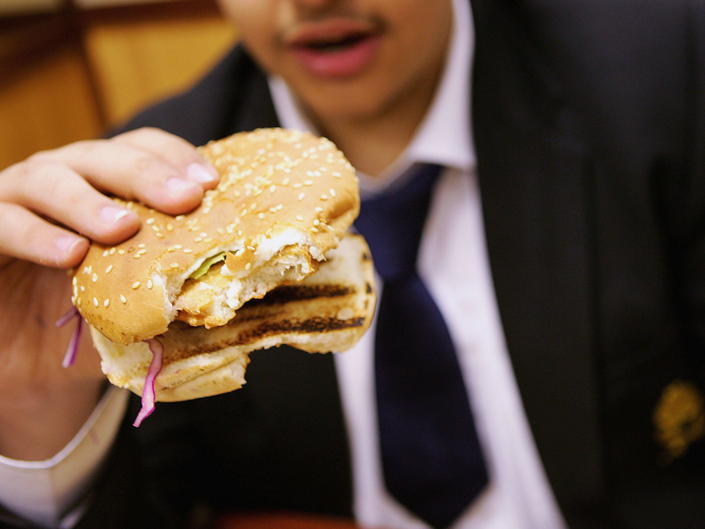 A school student eats a hamburger as part of his lunch