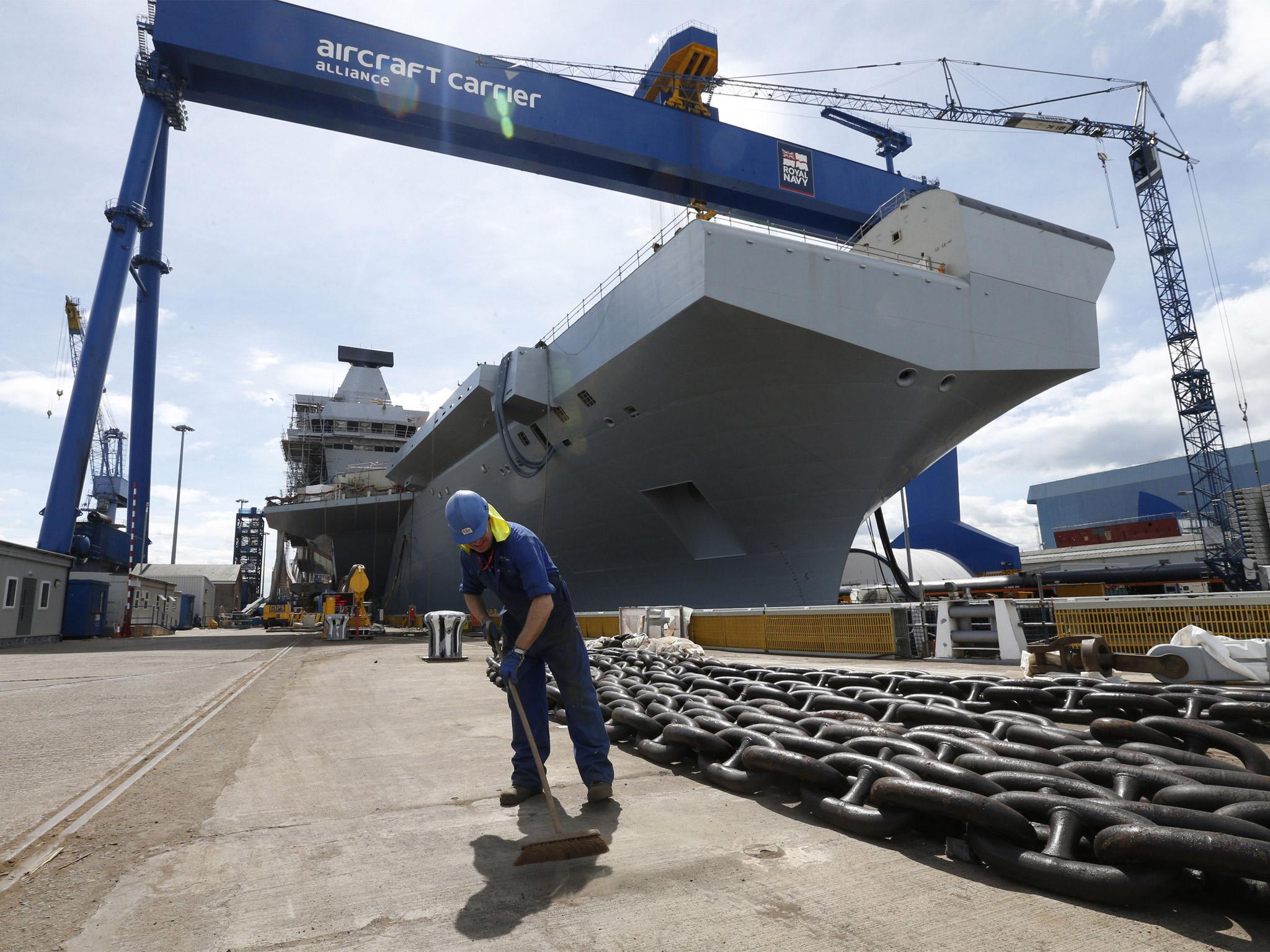 A worker sweeps in front of HMS Queen Elizabeth