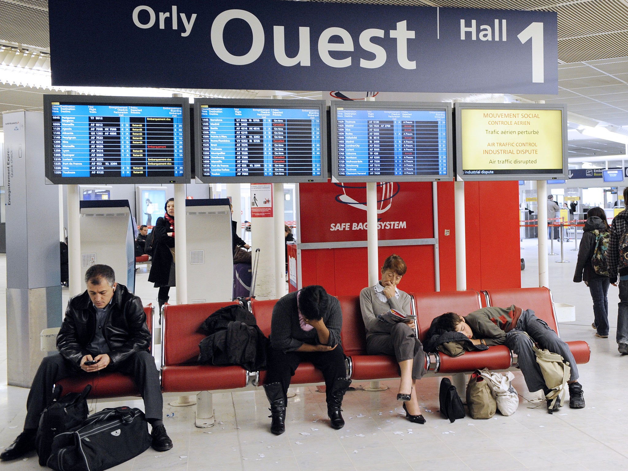 Passengers wait beside a screen announcing an air traffic control dispute on February 25, 2010 at Paris' Orly airport. Several flights were canceled or delayed as air traffic controllers went on strike to protest against an air traffic control European st