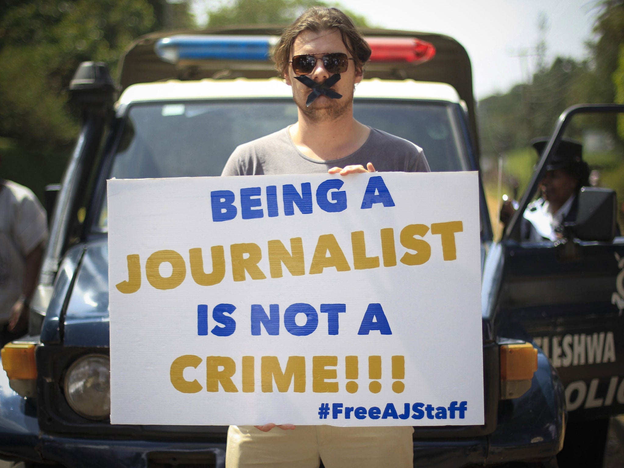 A Nairobi-based foreign correspondent posing with a placard to protest against imprisonment of Al-Jazeera journalists Peter Greste and his colleagues in Egypt, outside the Egyptian embassy in Kenya (EPA)