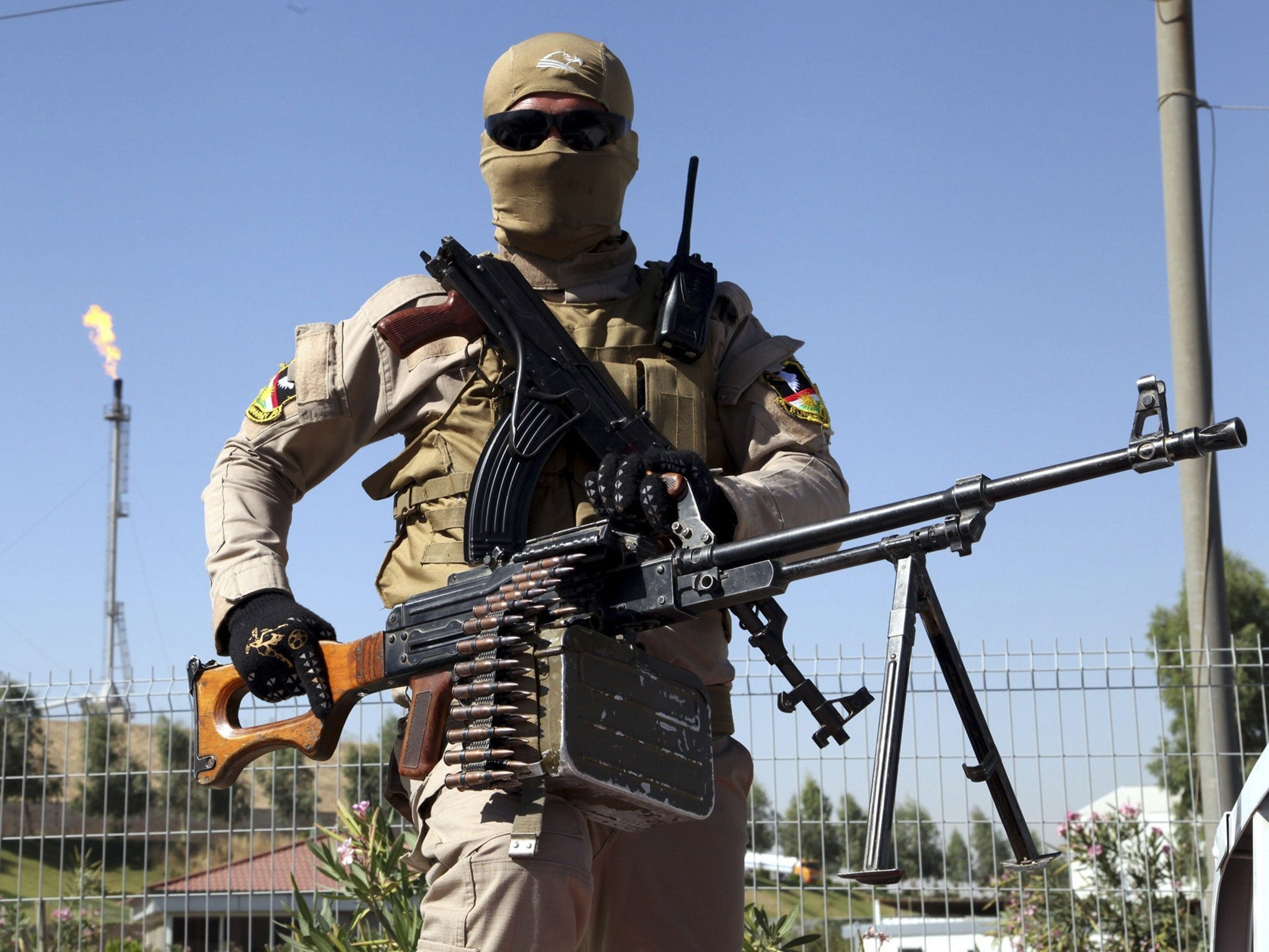 A member of the Kurdish security forces takes up position with his weapon while guarding an oil refinery, on the outskirts of Mosul