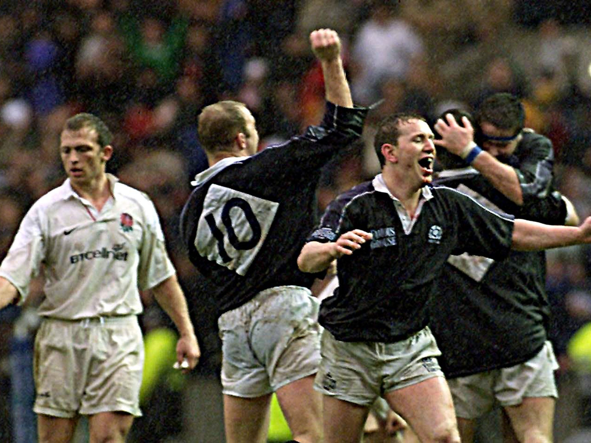 England's captain Matt Dawson (left) walks towards the jubilating Scottish captain Andy Nicol (foreground) with Duncan Hodge (No.10) after they beat England