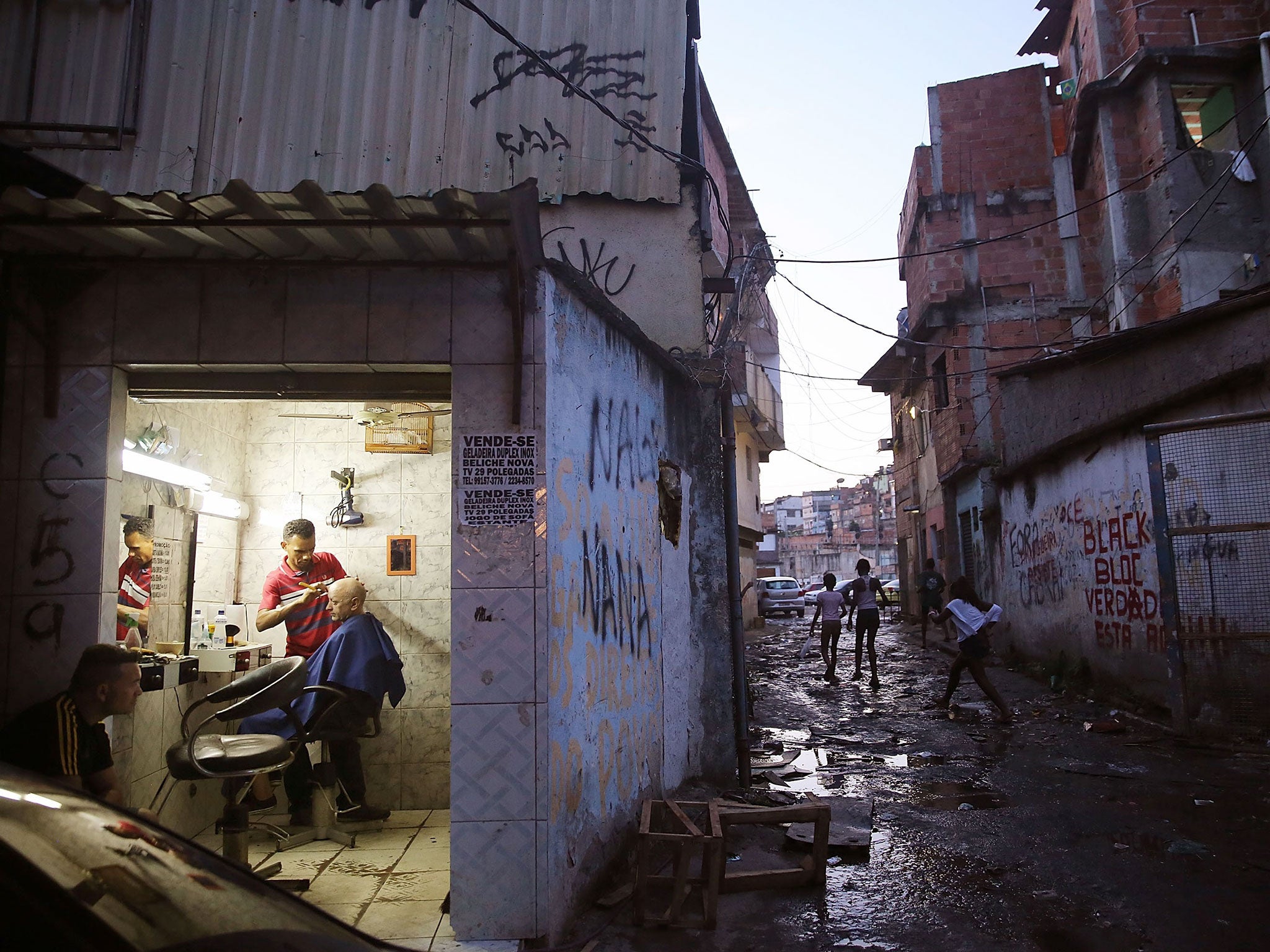 A man receives a haircut in the Metro Mangueria favela