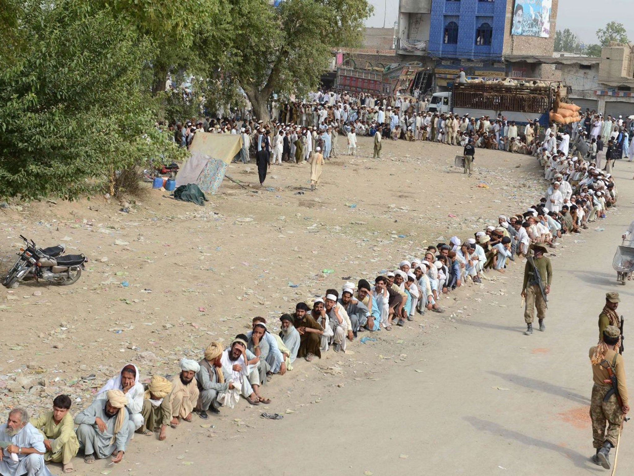 The displaced wait for hours in the blazing heat for help