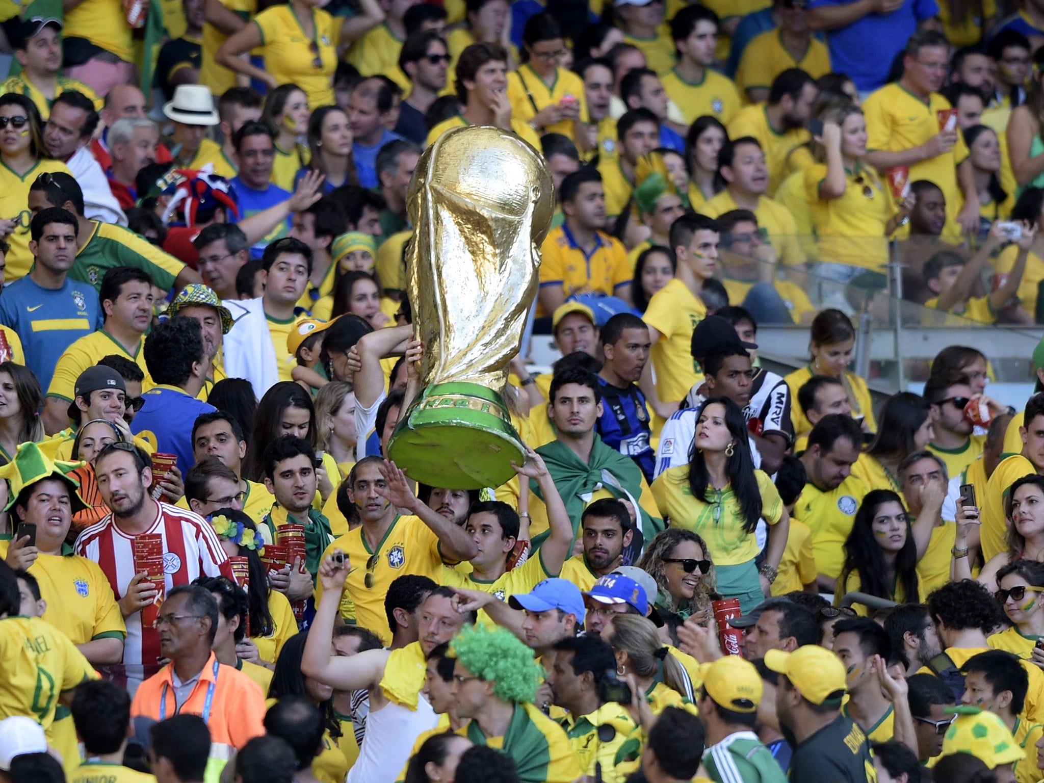 Brazilian fans hold a replica of the World Cup during extra-time in the Round of 16 football match between Brazil and Chile at The Mineirao Stadium