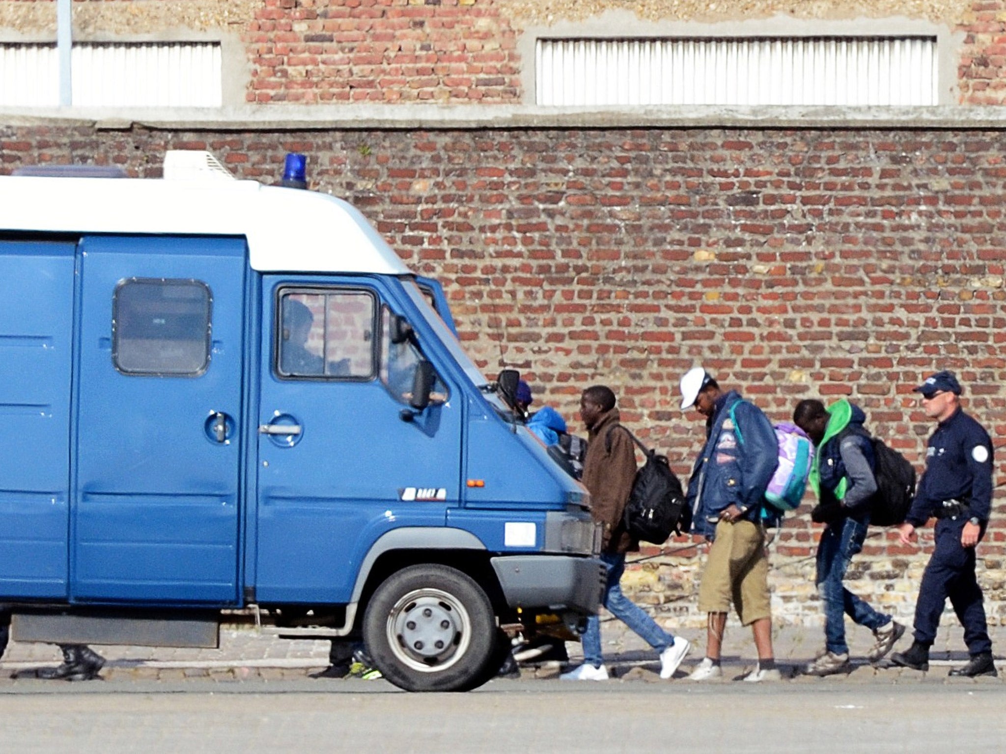 Migrants are led into a French police van (Getty)