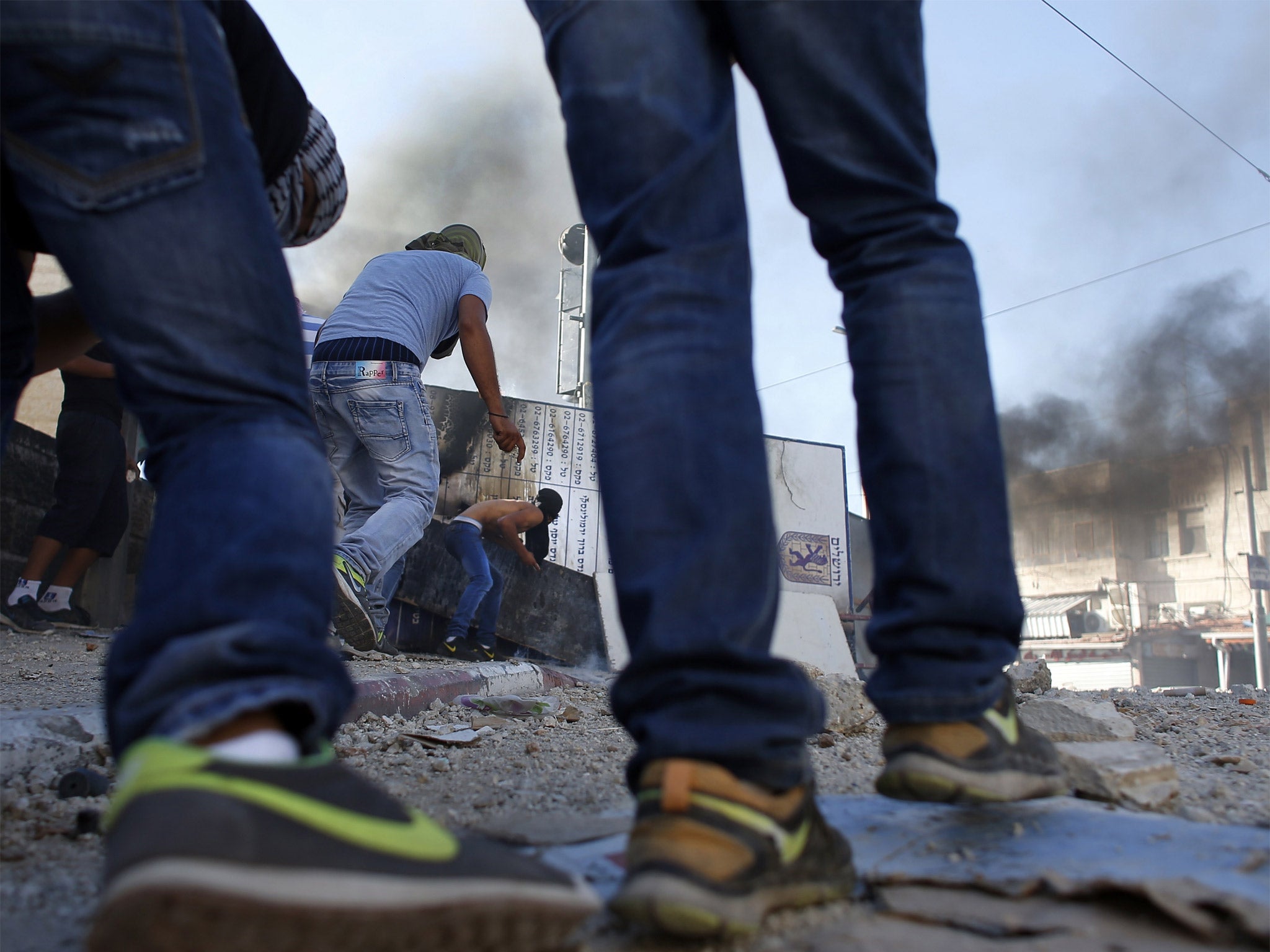 Masked Palestinian protesters throw stones toward Israeli police during clashes in the Shuafat neighborhood in Israeli-annexed Arab East Jerusalem
