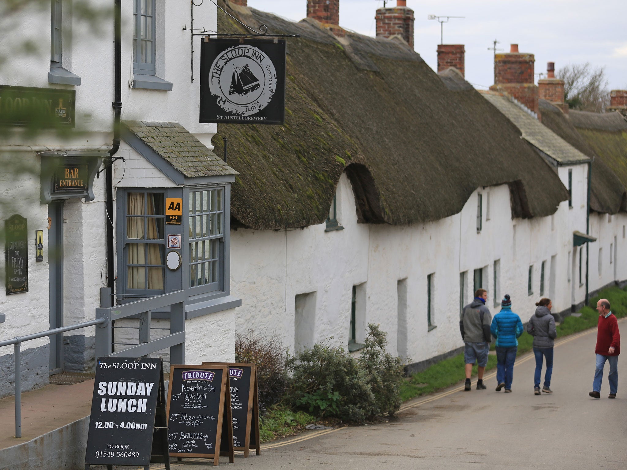 People walk past the local pub in the picturesque seaside village of Bantham