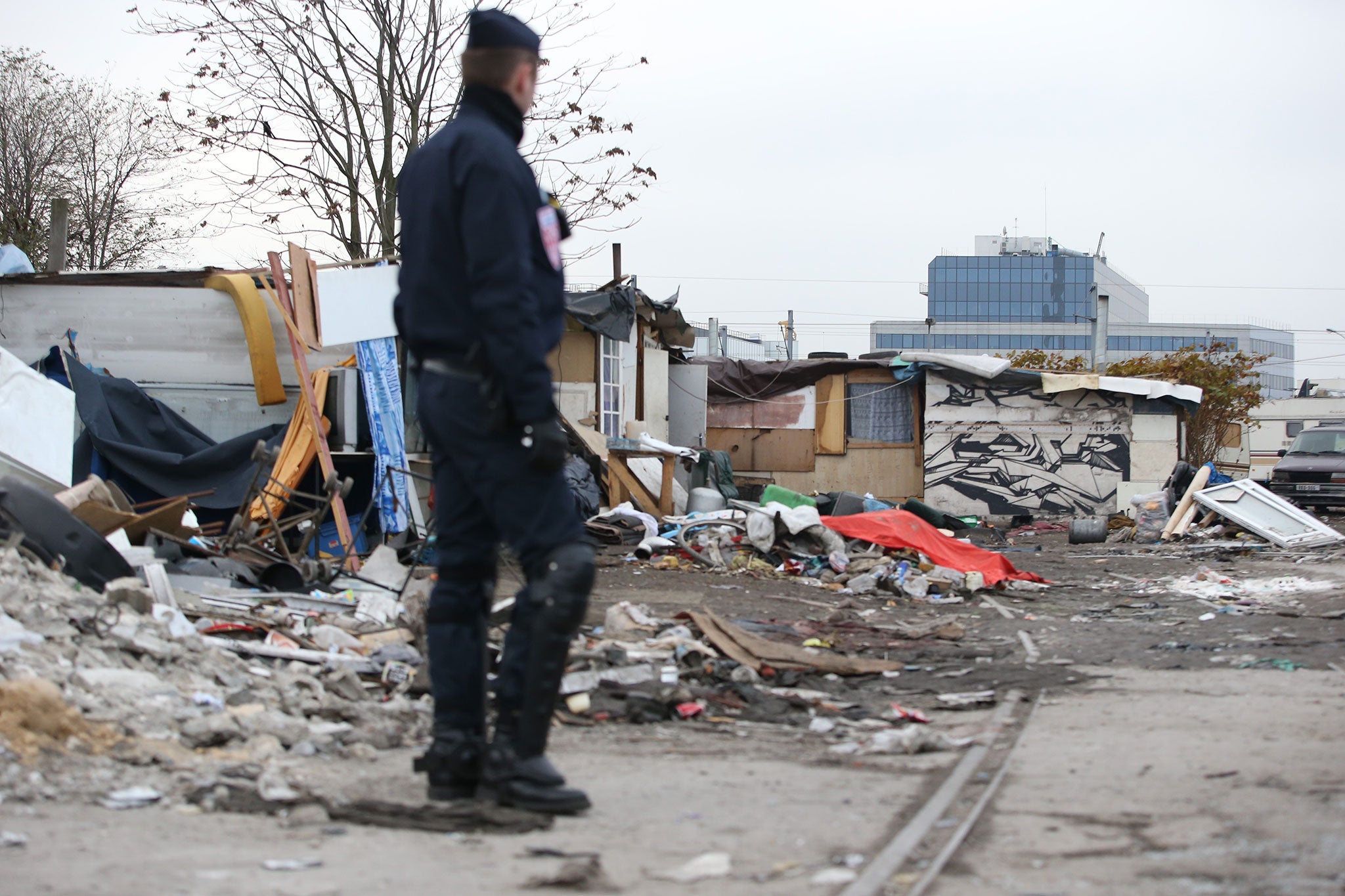 A policeman stands in a camp, where some 800 people of the Roma community were living