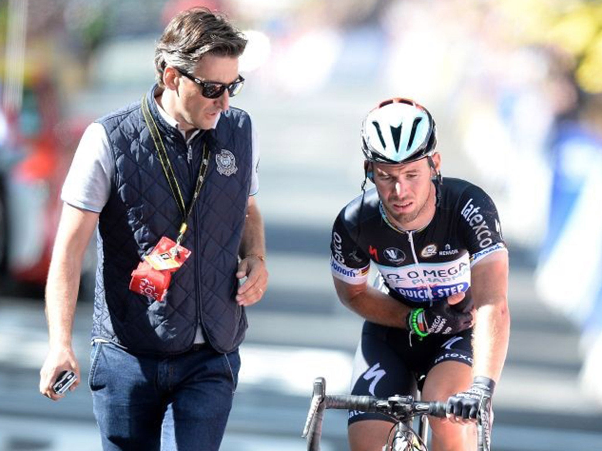 Yorkshire grit: A marshall looks concerned as an injured Mark Cavendish struggles on after his clash with Simon Gerrans and rides over the line