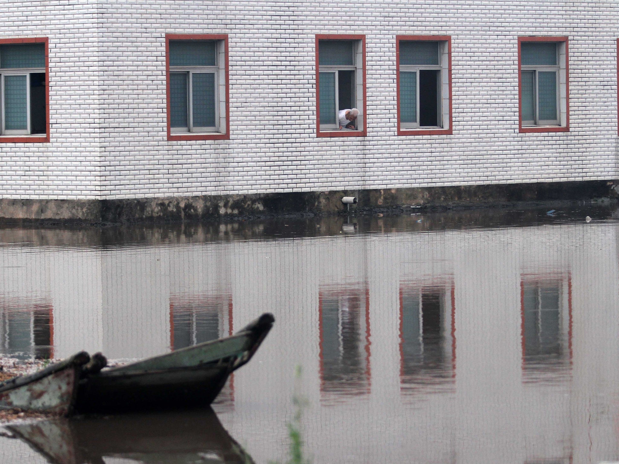 A resident looks out from a window in a building surrounded by flood water in Xiamen, east China's Fujian province.