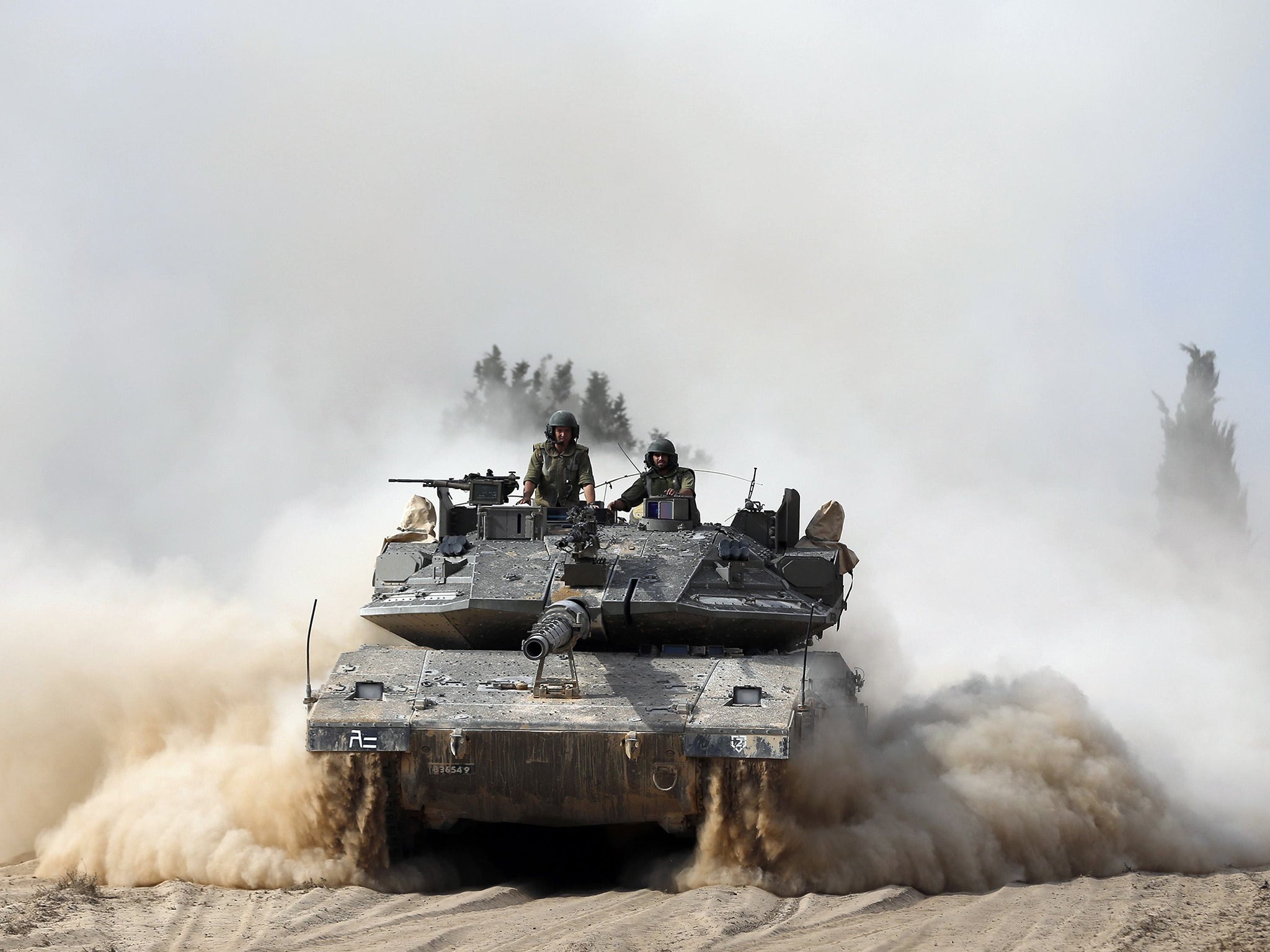 Israeli soldiers ride atop a tank outside the southern Gaza Strip.