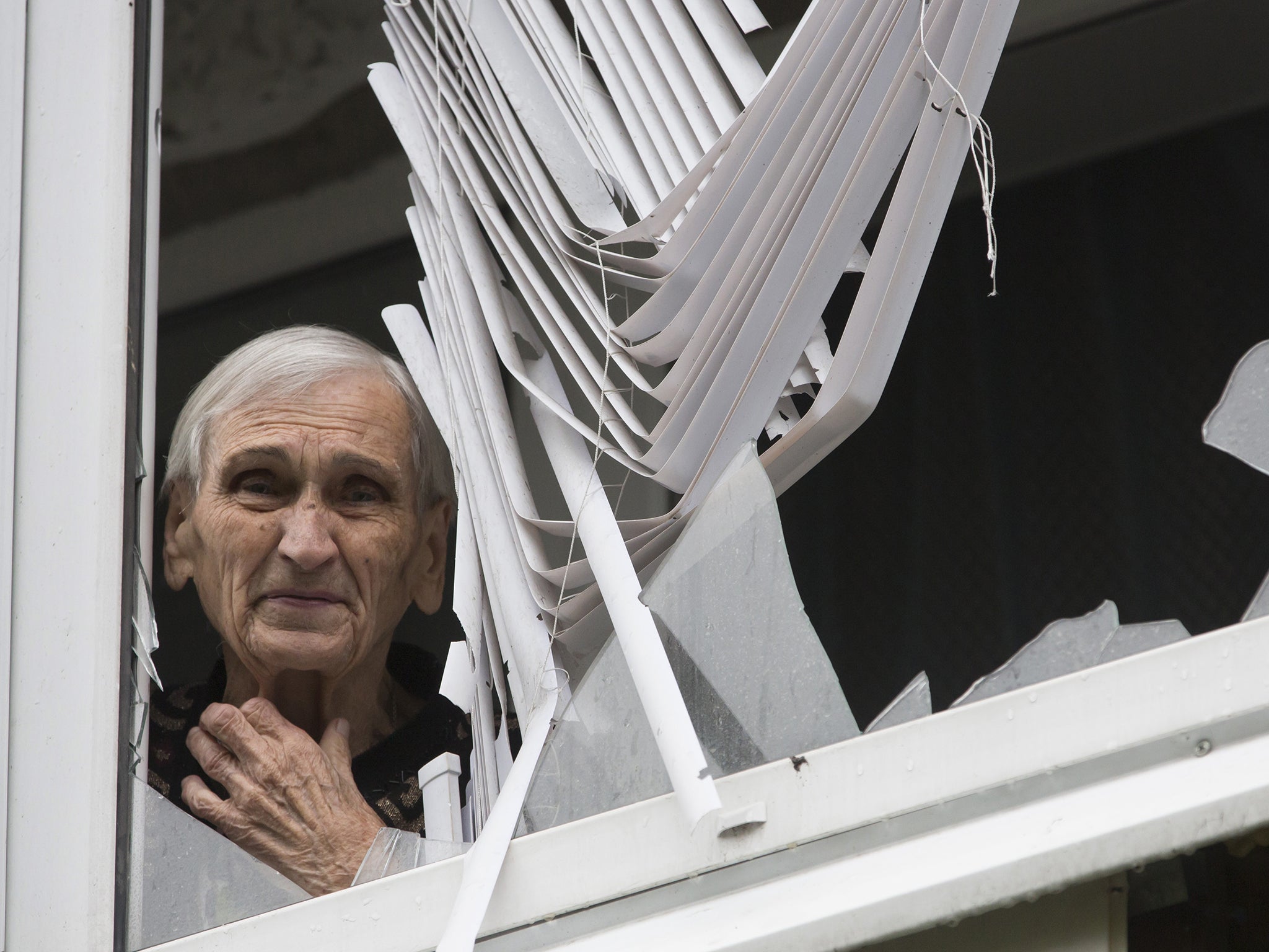 A woman looks out from her damaged house in the city of Slovyansk