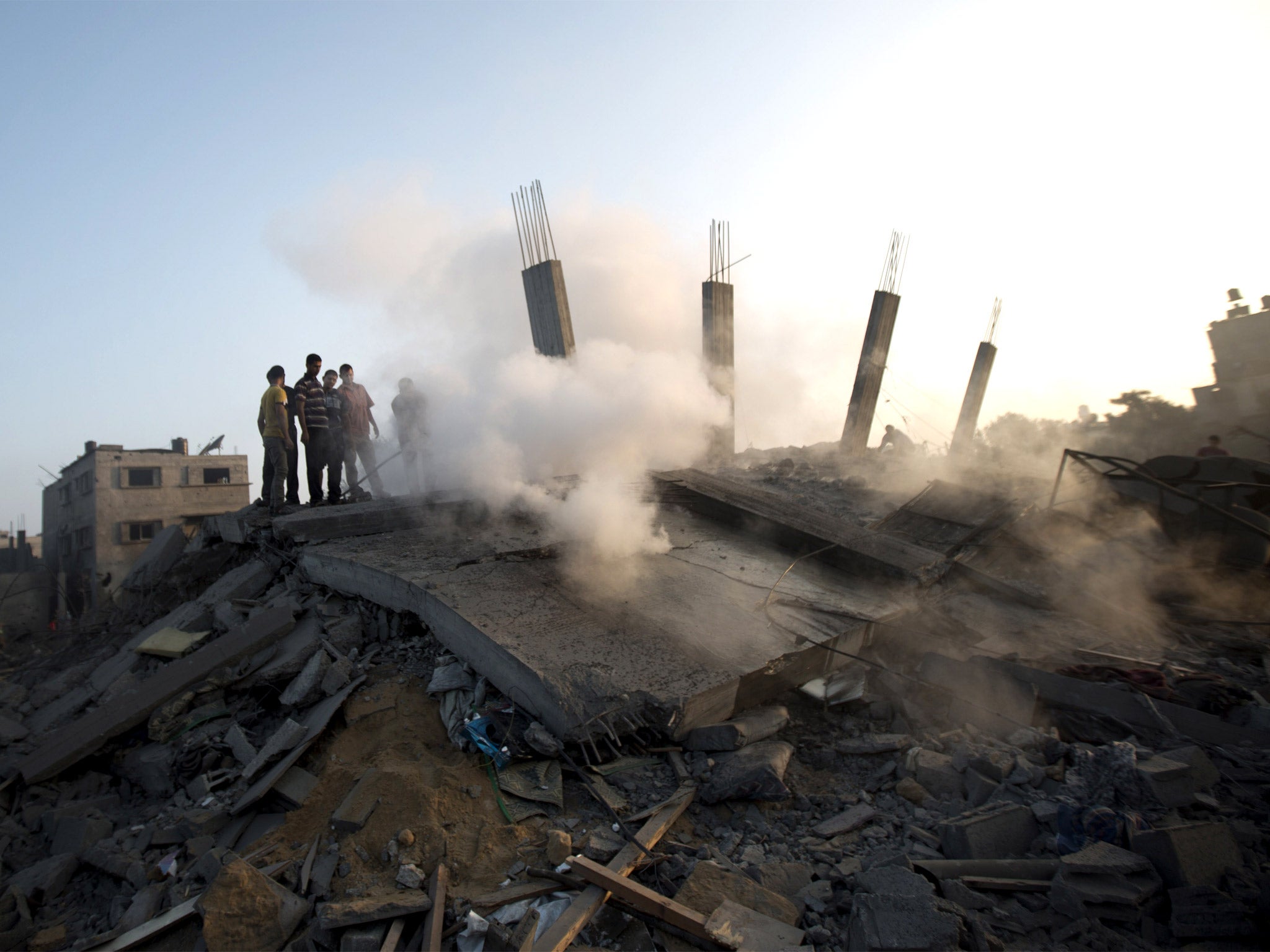 Palestinians walk over the rubble of a building destroyed by an Israeli air strike on Gaza City