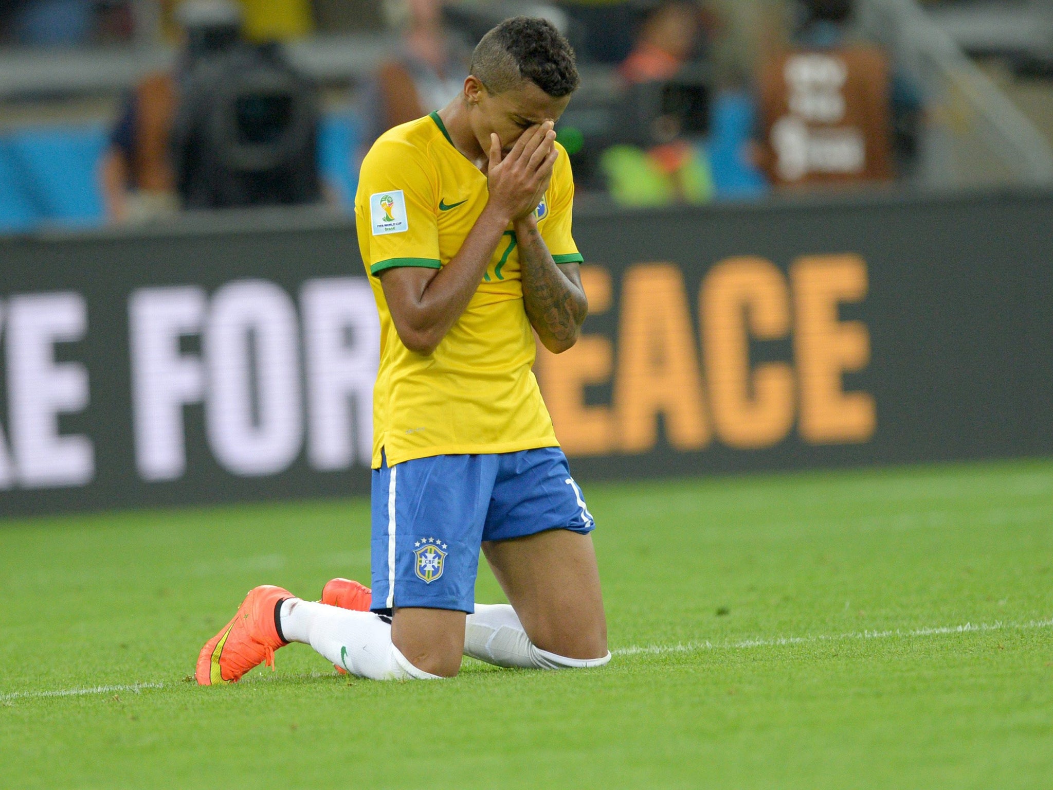 Brazil's Luis Gustavo kneels on the pitch at the final whistle of the FIFA World Cup 2014 semi final match between Brazil and Germany at the Estadio Mineirao in Belo Horizonte, Brazil