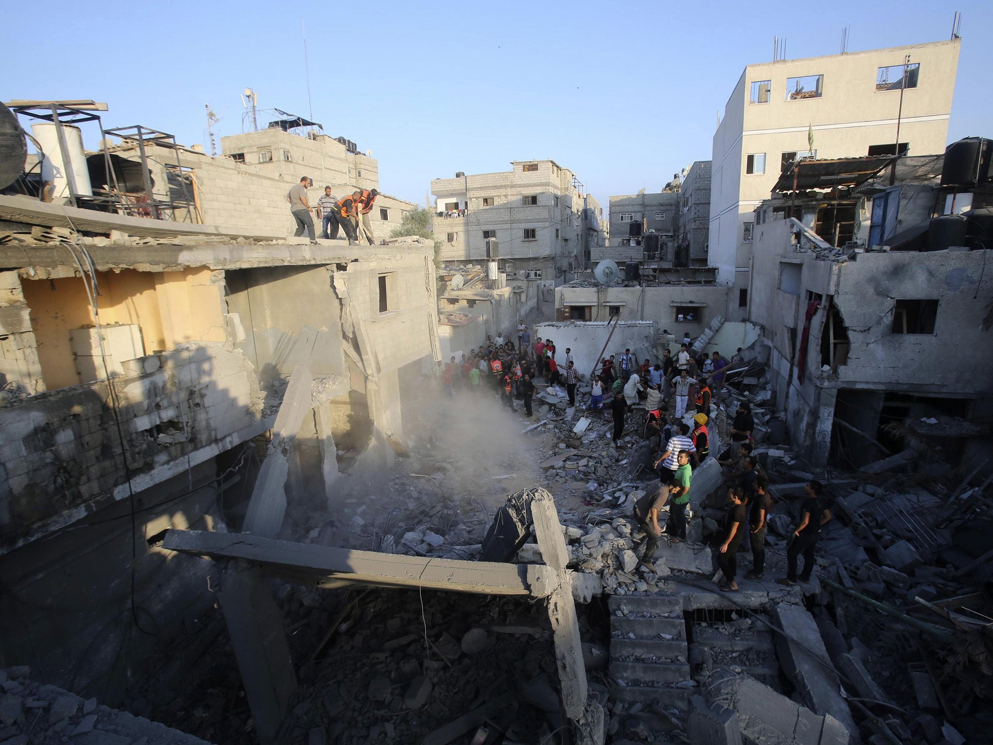 Palestinians and rescue workers stand near the rubble of a house which police said was destroyed in an Israeli air strike in Khan Younis in the southern Gaza Strip July 10, 2014