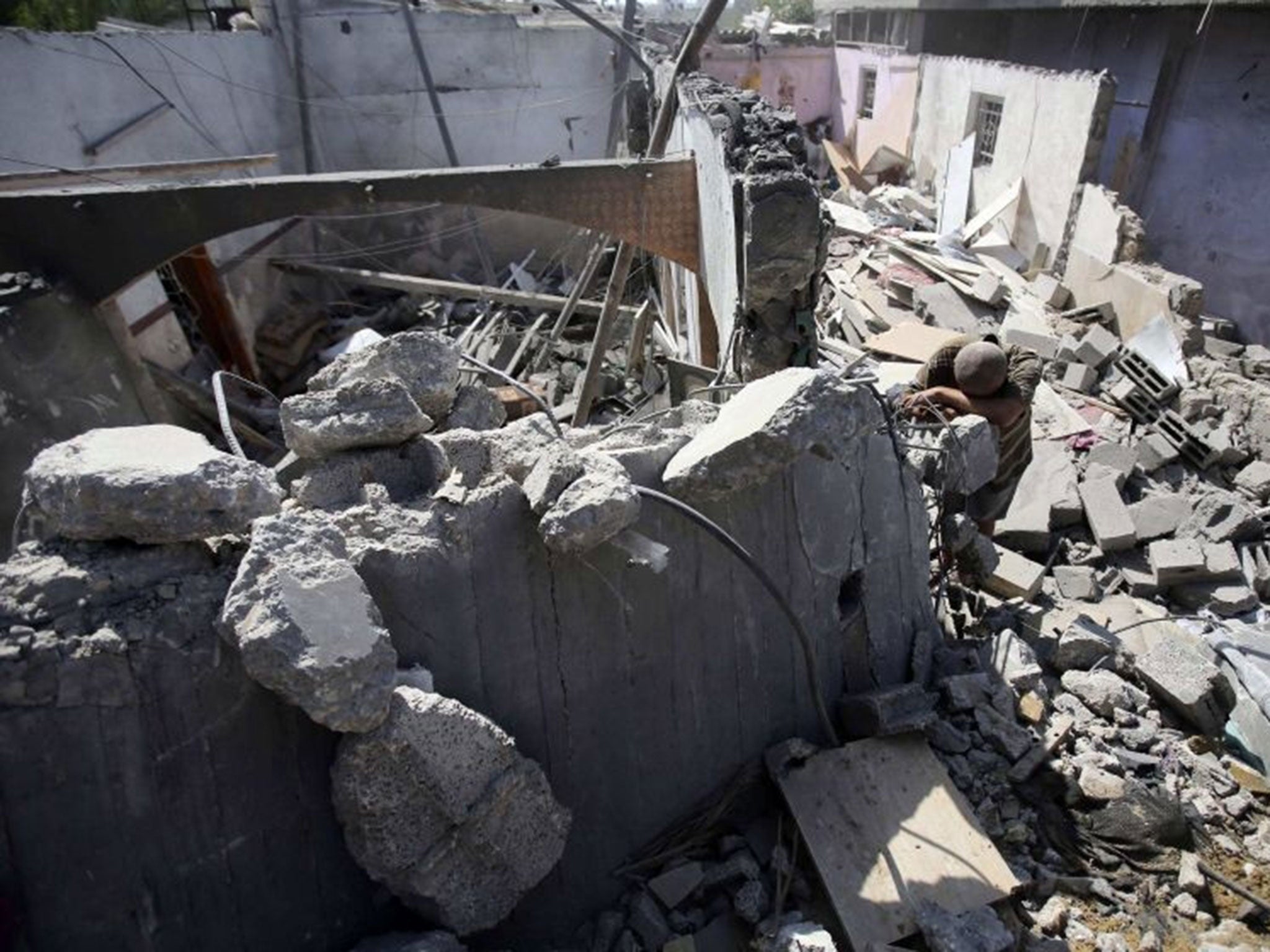 A Palestinian man leans over the rubble of his house which police said was destroyed in an Israeli air strike in Khan Younis in the southern Gaza Strip July 10, 2014. At least 74 Palestinians, most of them civilians, have been killed in Israel's Gaza offe