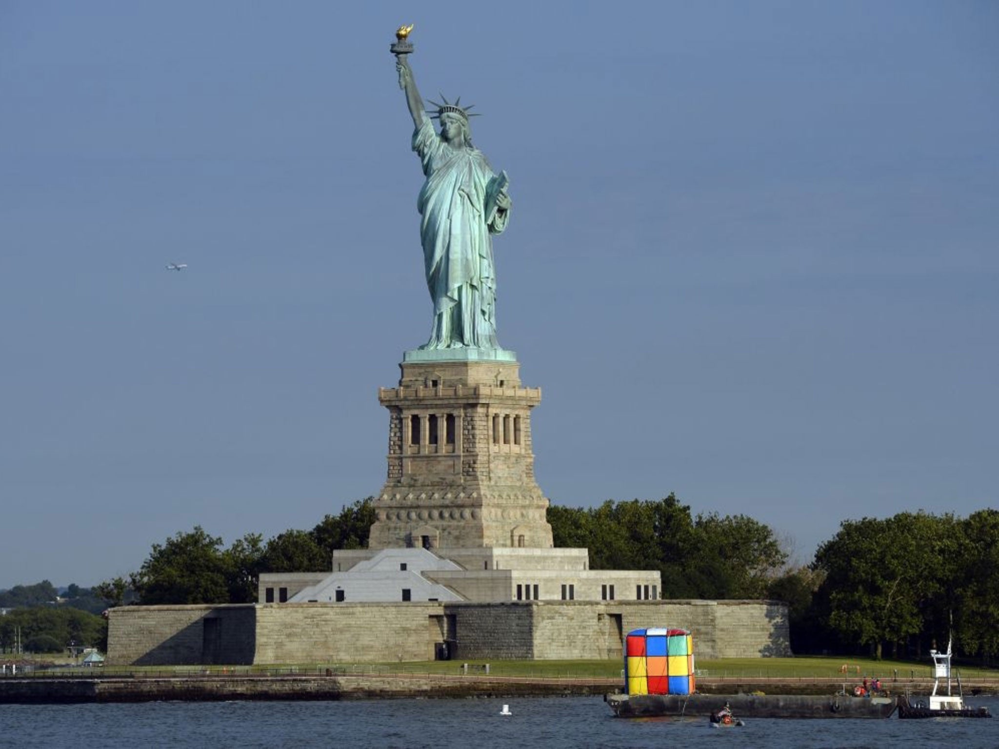 A tugboat tows a giant inflatable likeness of a Rubik's Cube puzzle near the Statue of Liberty on July 11, 2014 in New York to mark Hungarian architecture professor and inventor Erno Rubik turning 70 on July 13, the anniversary of his July 13, 1944, birt