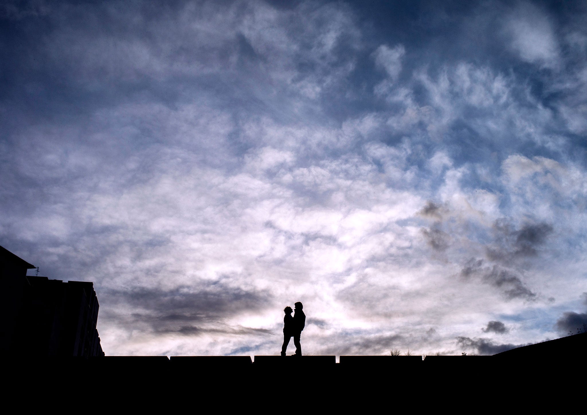 A couple stand in front of a beautiful cloudy scene