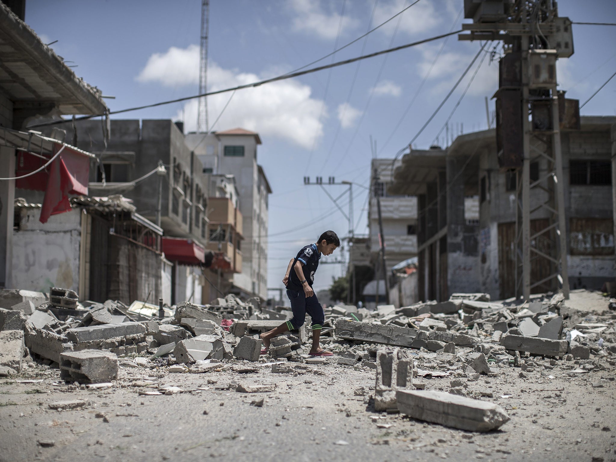 A young Palestinian boy walks over debris from a house that was destroyed in an airstrike in Deir Al Balah