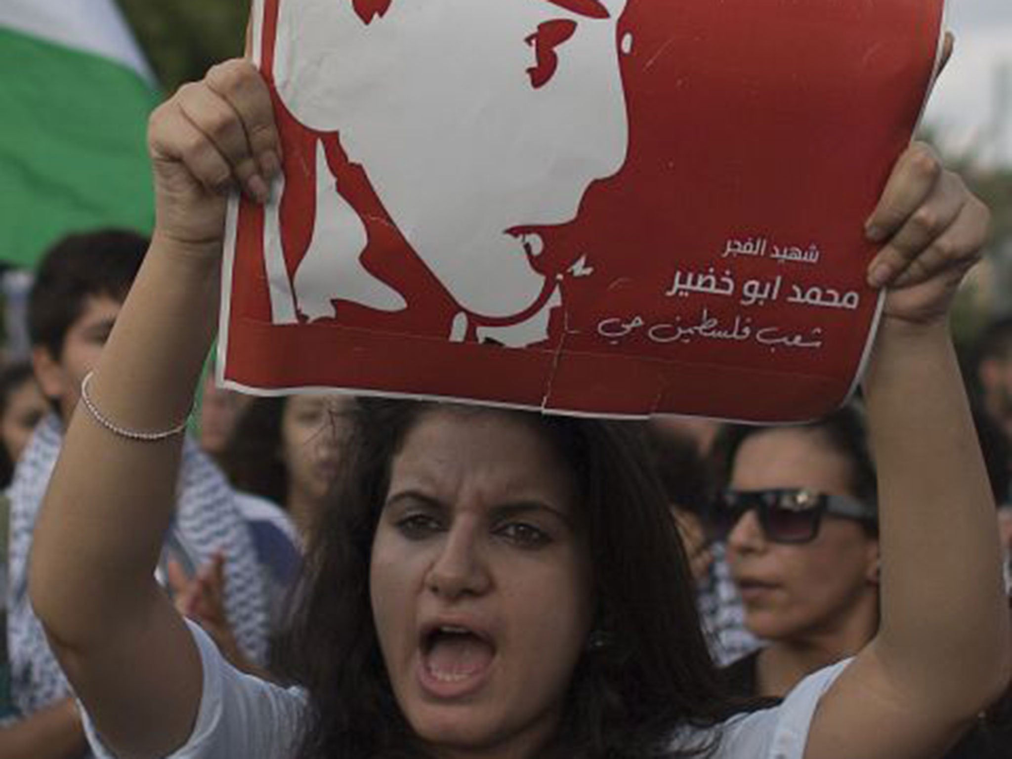 A protestor holding a portrait of Mohammed Abu Khder, a 16yr old Palestinian from east Jerusalem who was kidnapped and killed in a suspected revenge attack (AFP)