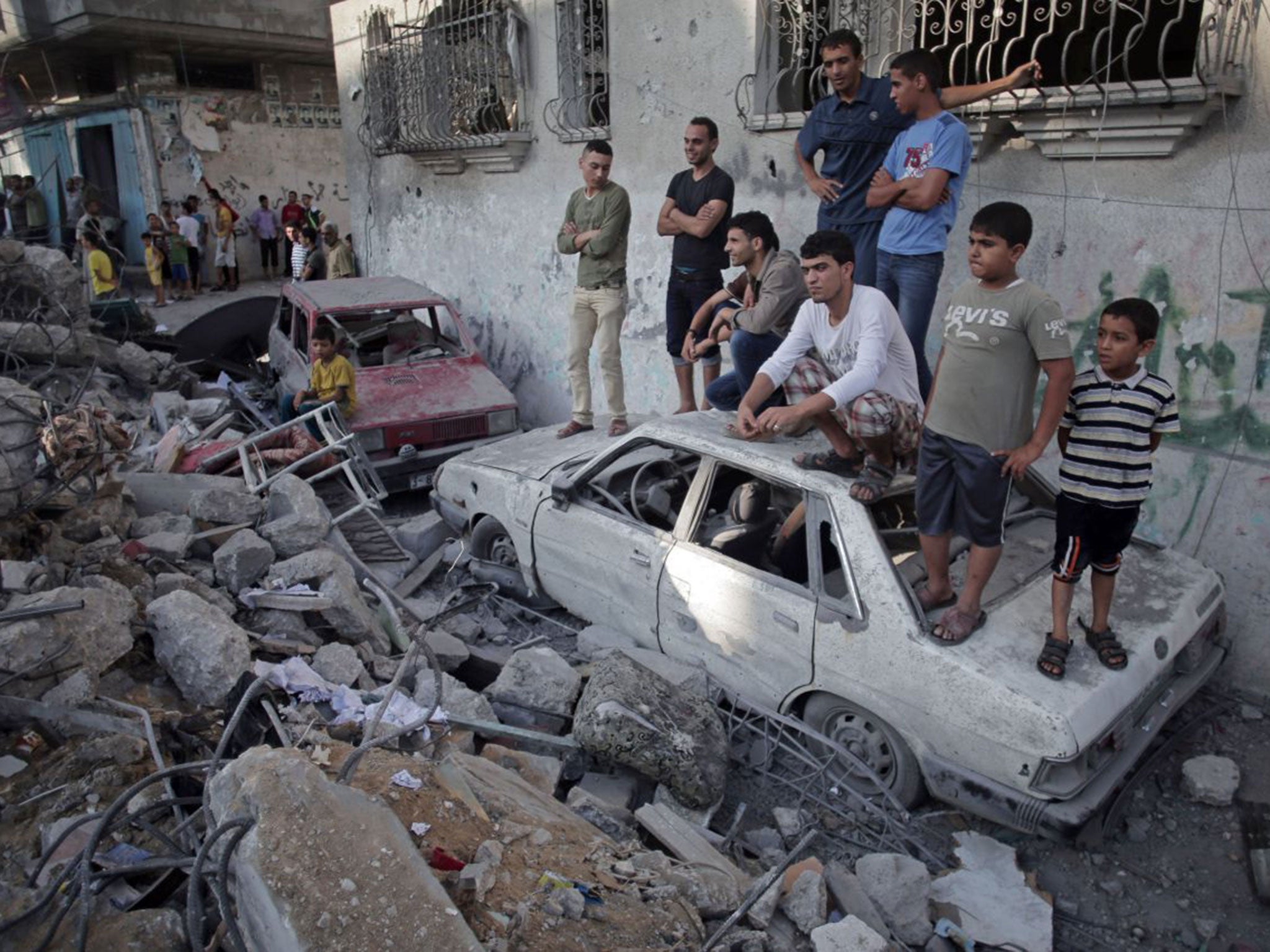 Palestinians gather outside the ruins of the house where five members of the Ghannam family were killed in an Israeli missile strike