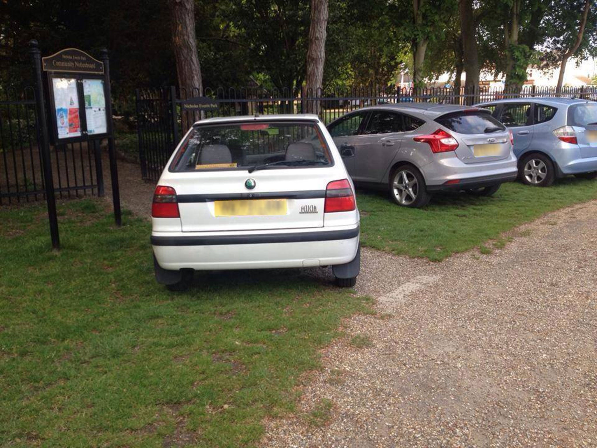 A car blocks the entrance to a park in this image