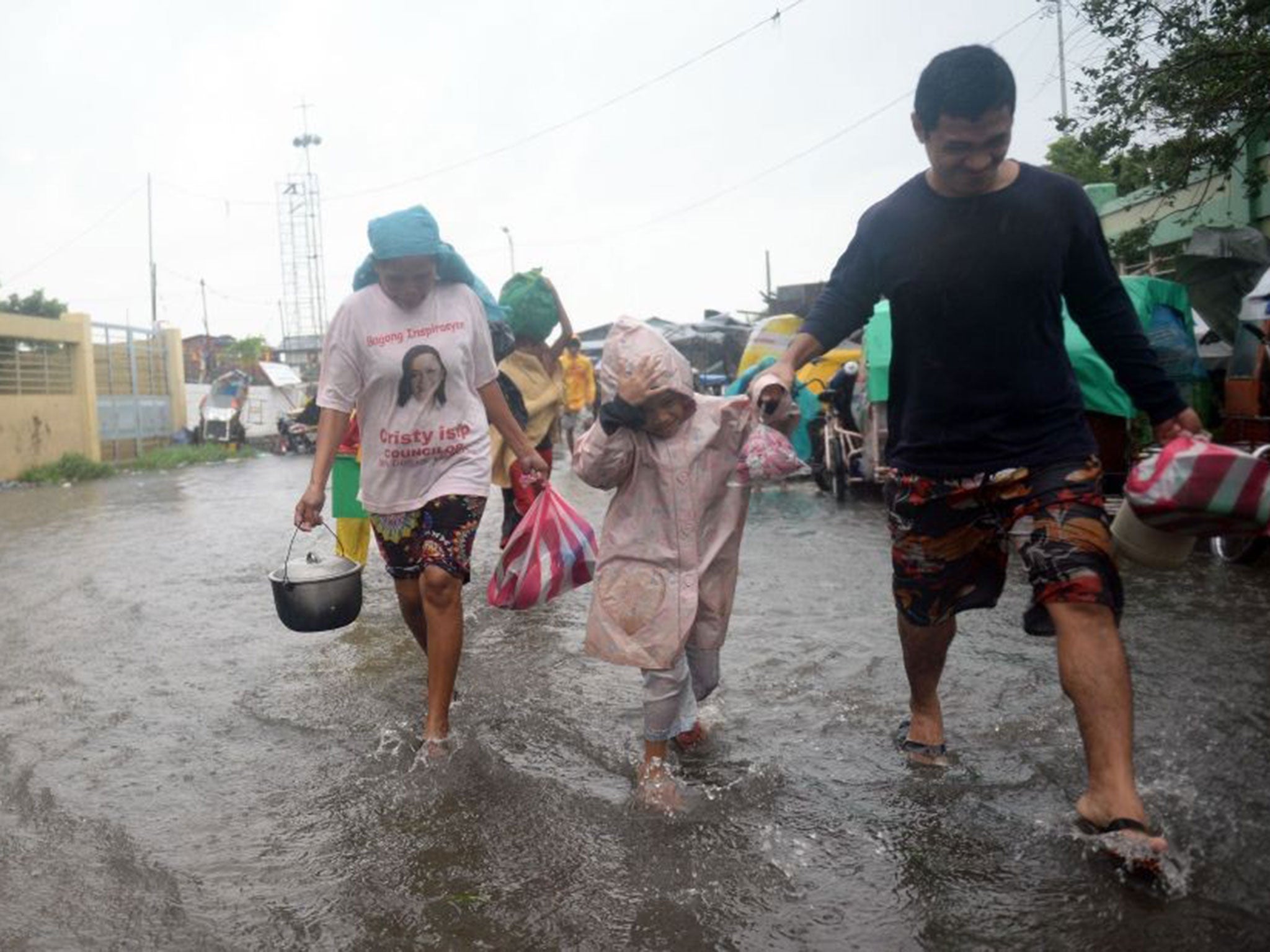 Residents cross a flooded street to an evacuation center as Typhoon Rammasun/Glenda barrels across Manila