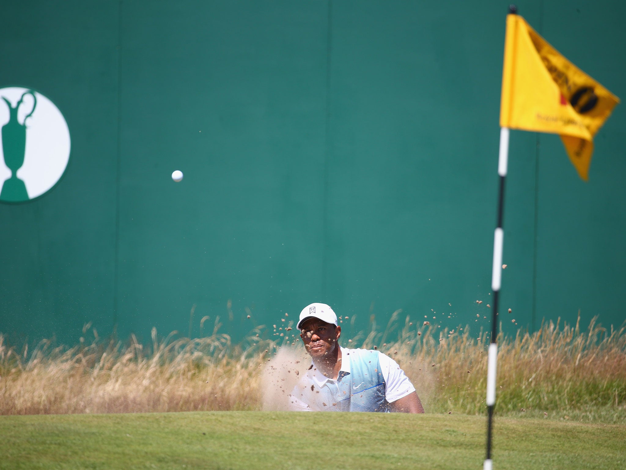 Woods hits from a bunker on the 18th hole