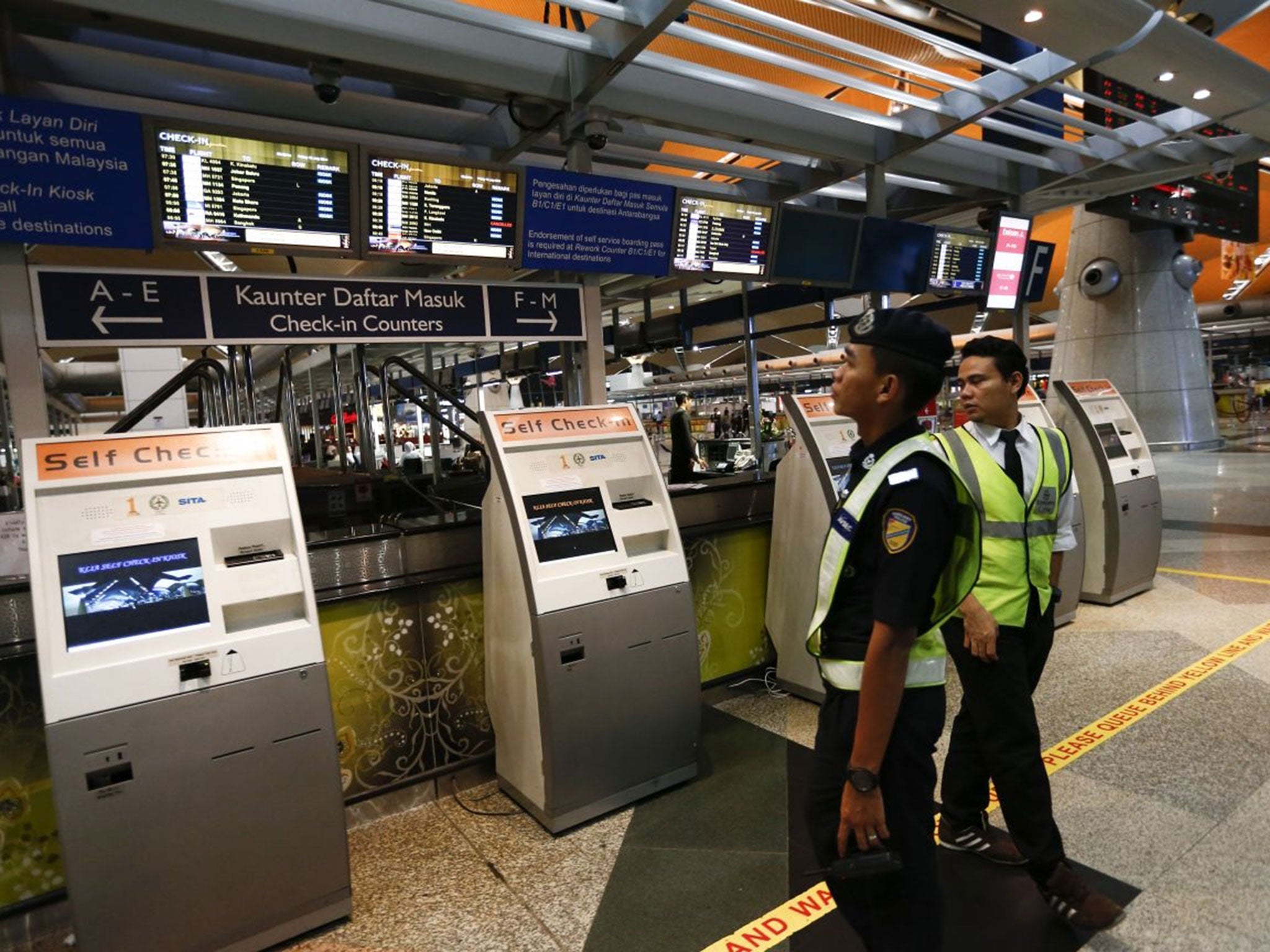 Airport security personnel look at the flight information board in the departure hall, at Kuala Lumpur International Airport, where flight MH17 was flying to