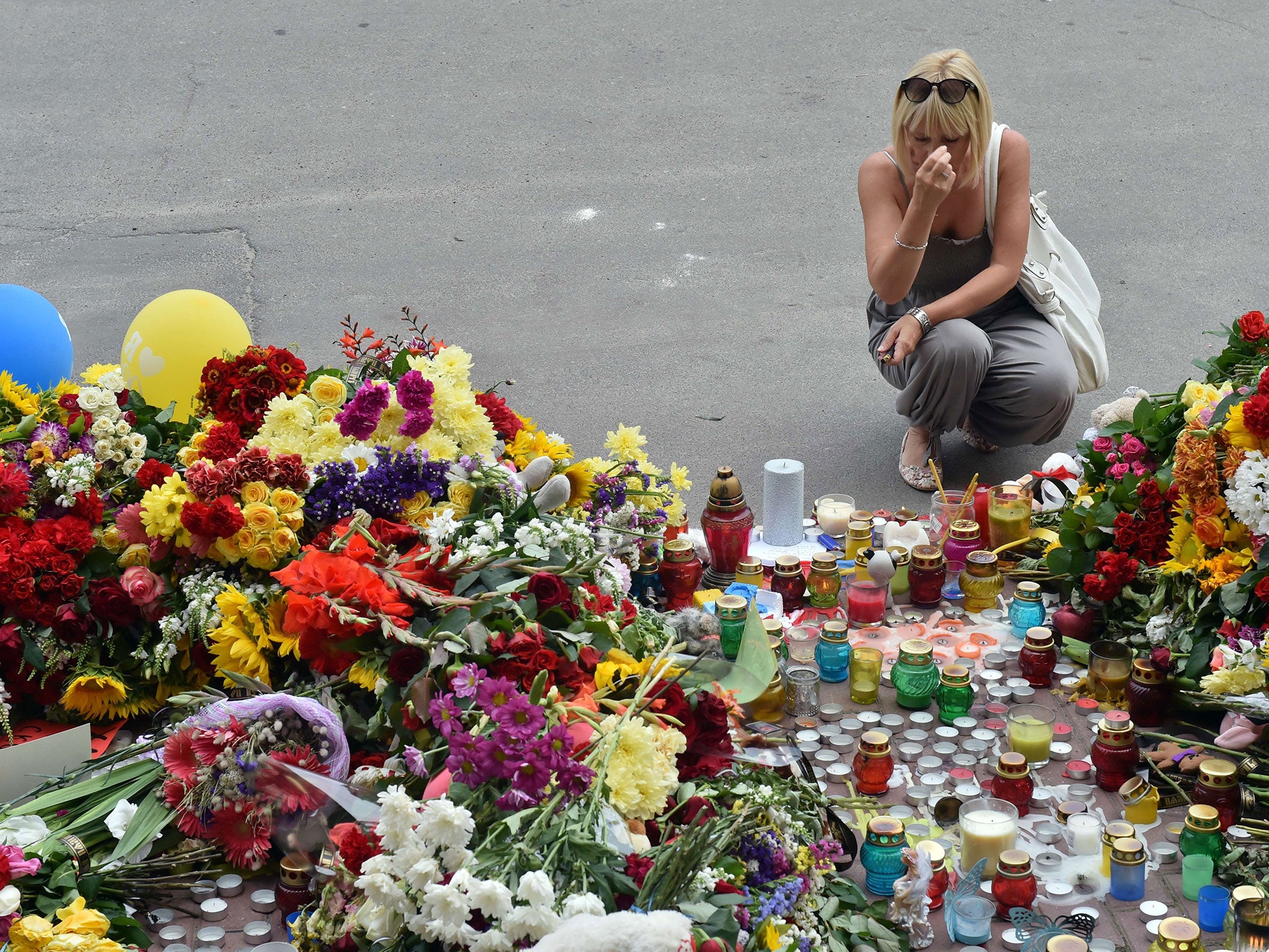 A woman crosses herself amid flowers and candles outside the Dutch Embassy in Kiev yesterday