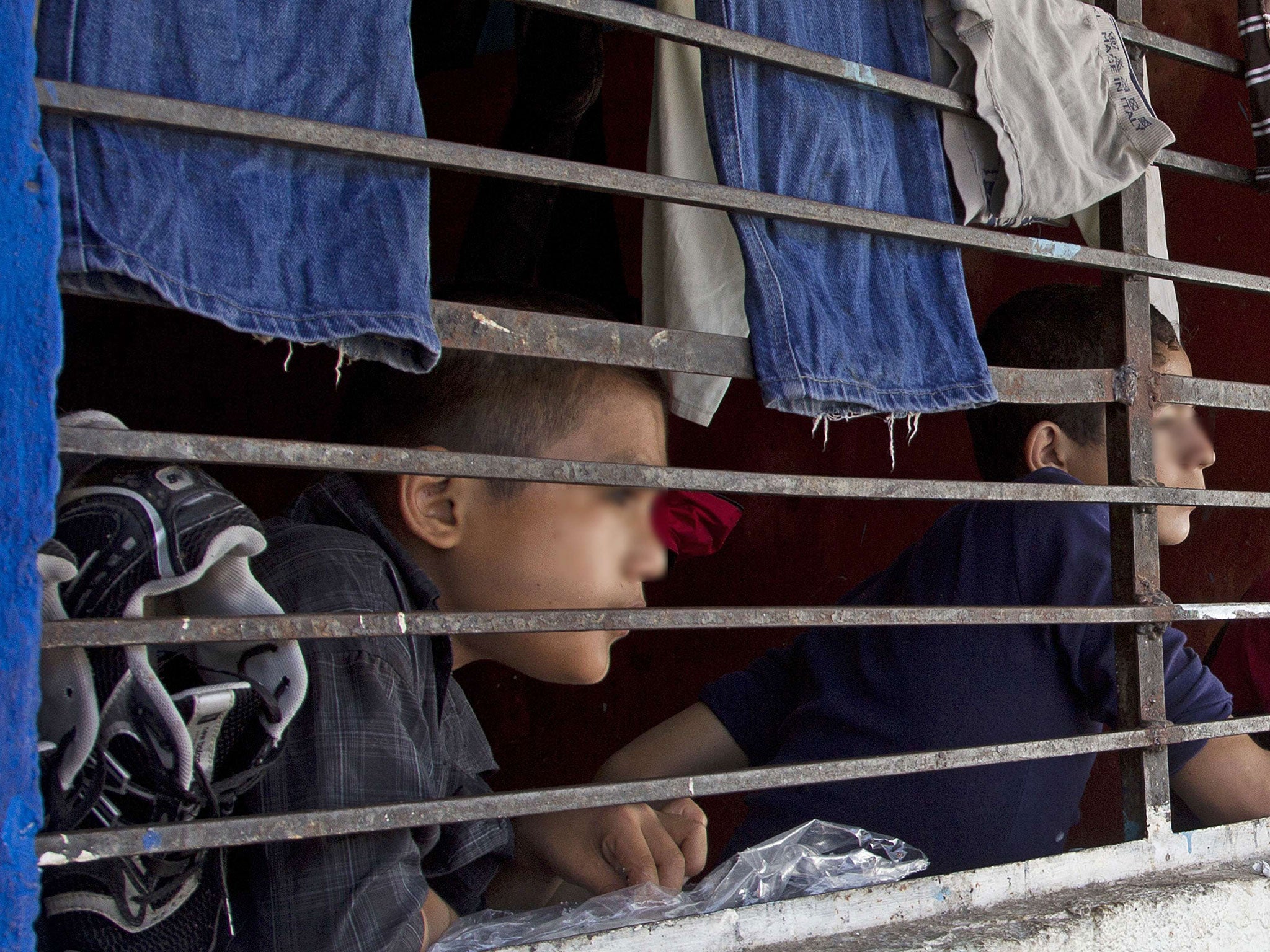 Children watch through a barred window inside "La Gran Familia"