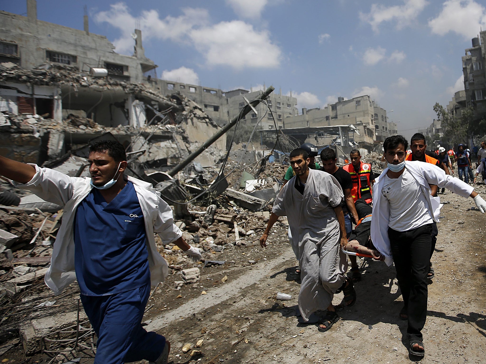 Palestinians paramedics lift the body of a man from the Al Shejaeiya neighbourhood, during a brief period of ceasefire requested by local rescue forces to retrieve dead and wounded from the Shuja'iyya neighbourhood in east Gaza City