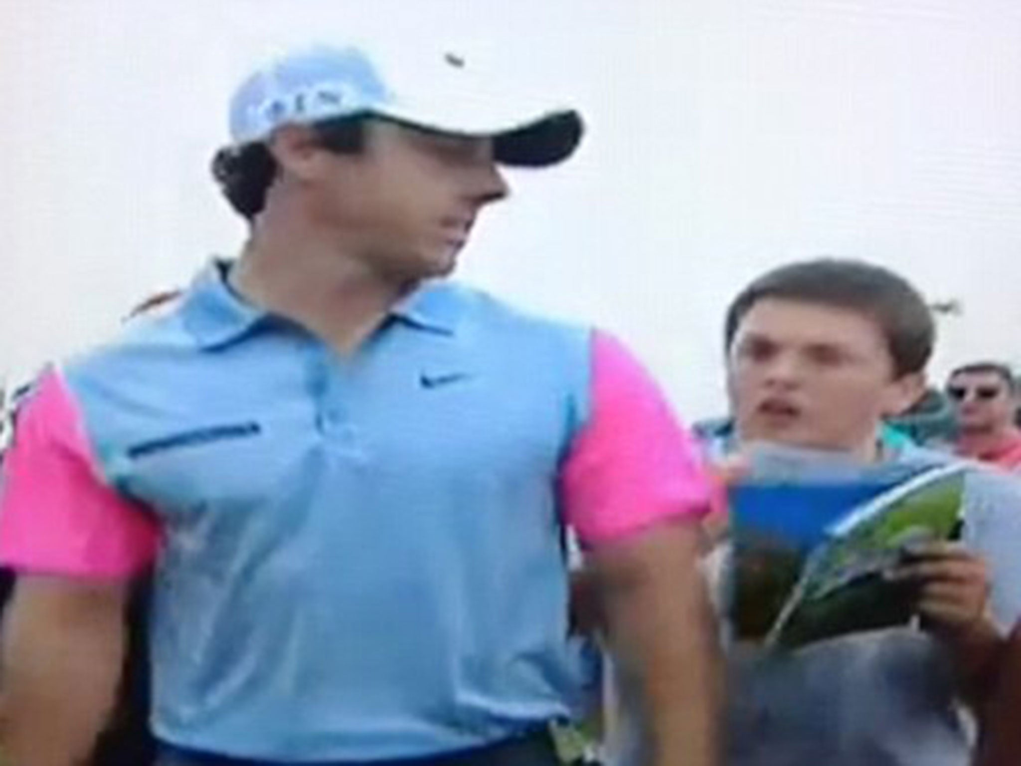 McIlroy looks at the youngster as he makes his way to sign for his scorecard