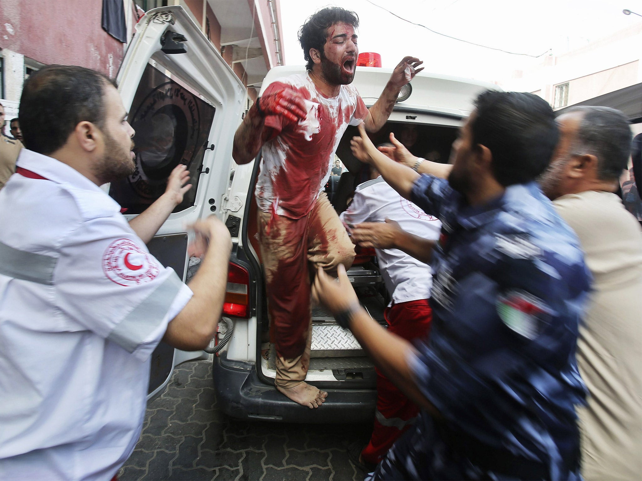 A Palestinian man, in clothes stained with the blood of his father, who medics said was killed by Israeli shelling, mourns as he disembarks an ambulance transporting his father's body, at a hospital in Khan Younis