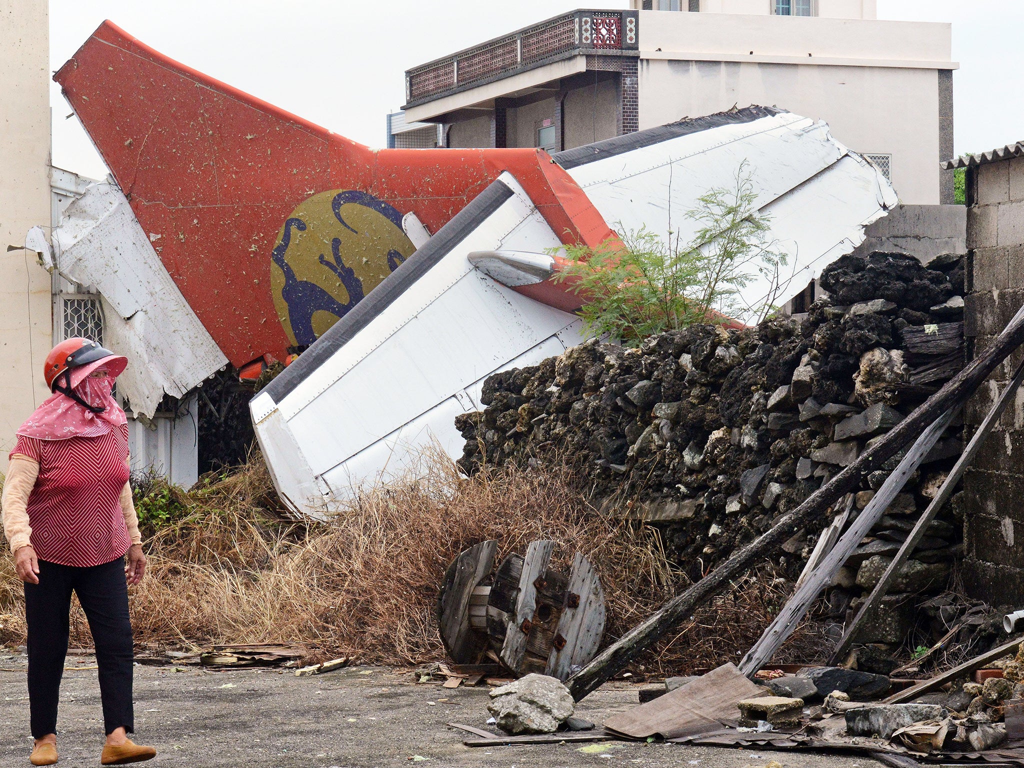 A local resident walks past the tail section of TransAsia Airways flight GE222